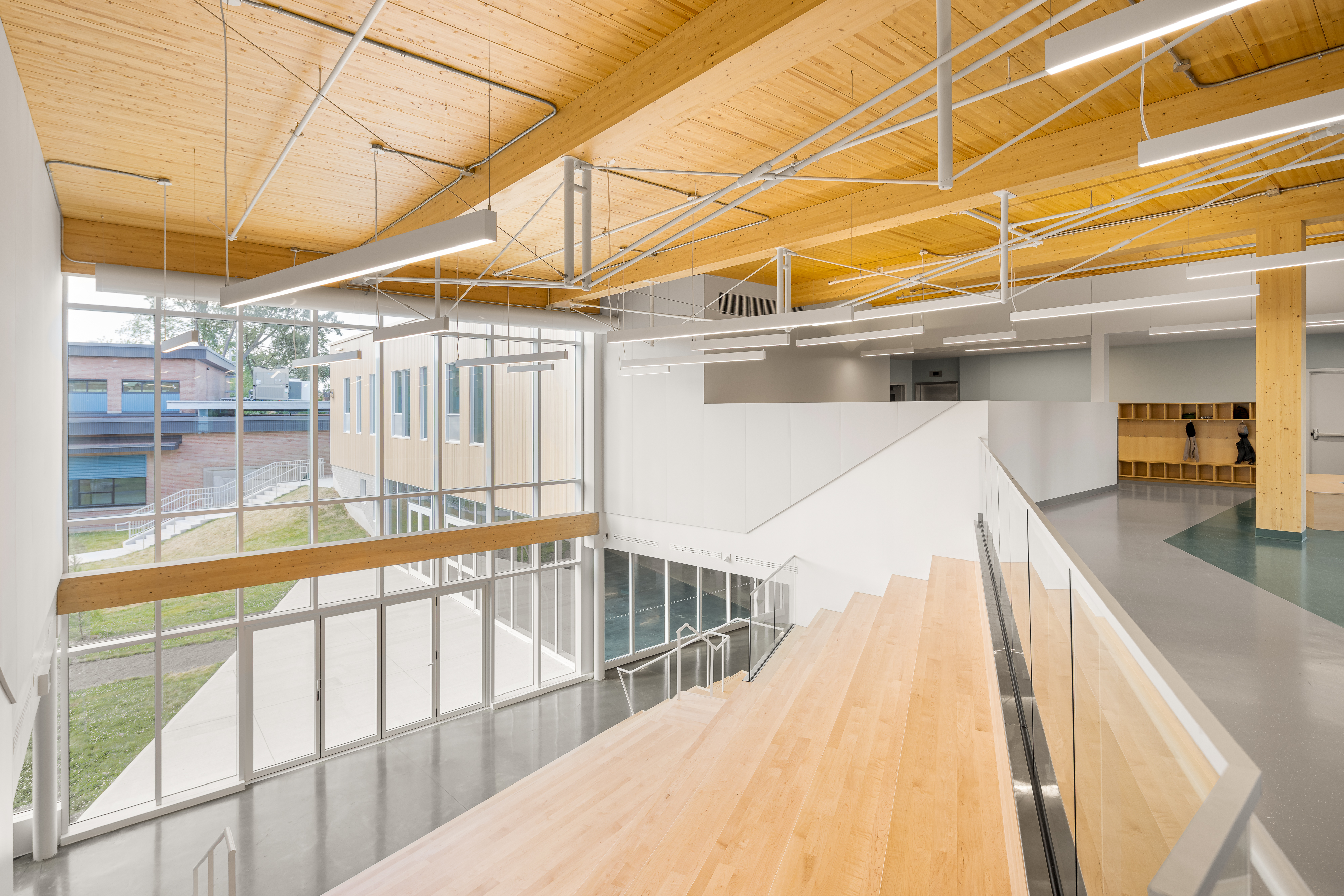 Photographie d’architecture d’un espace intérieur scolaire avec structure apparente en bois et design contemporain.