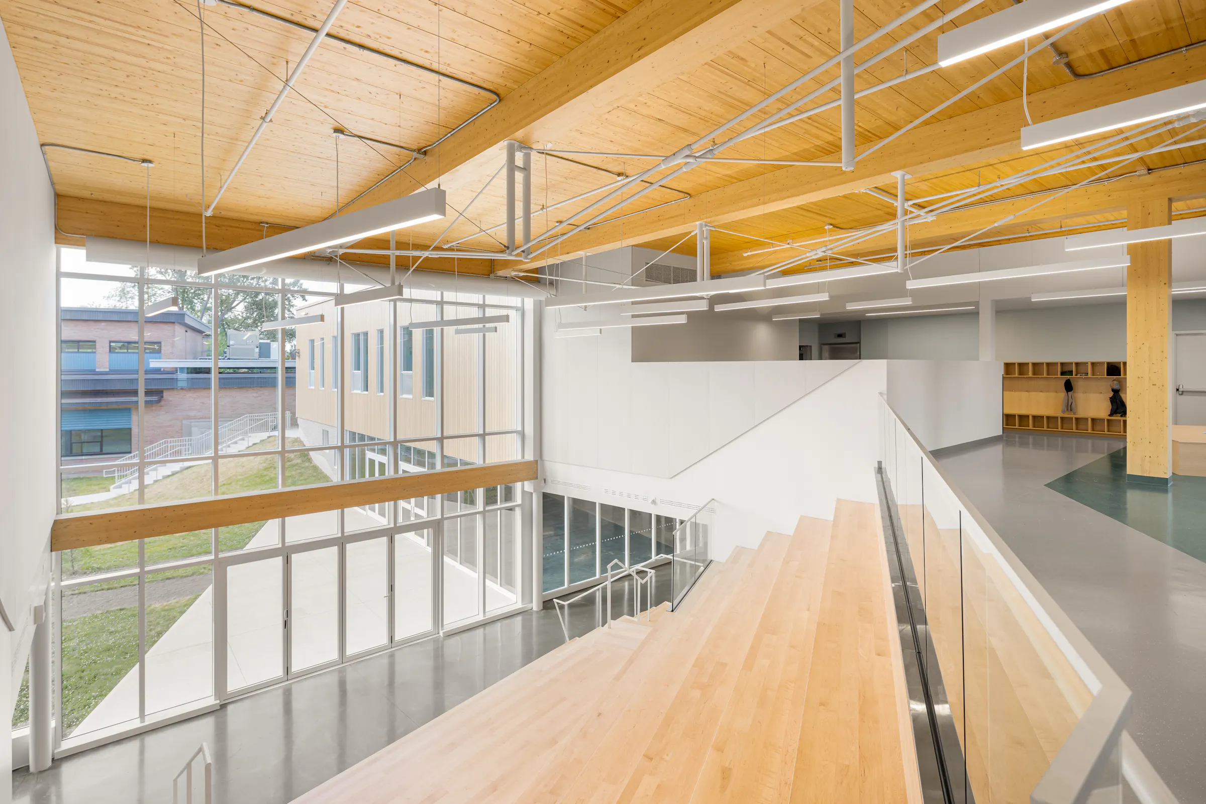 Photographie d’architecture d’un espace intérieur scolaire avec structure apparente en bois et design contemporain.