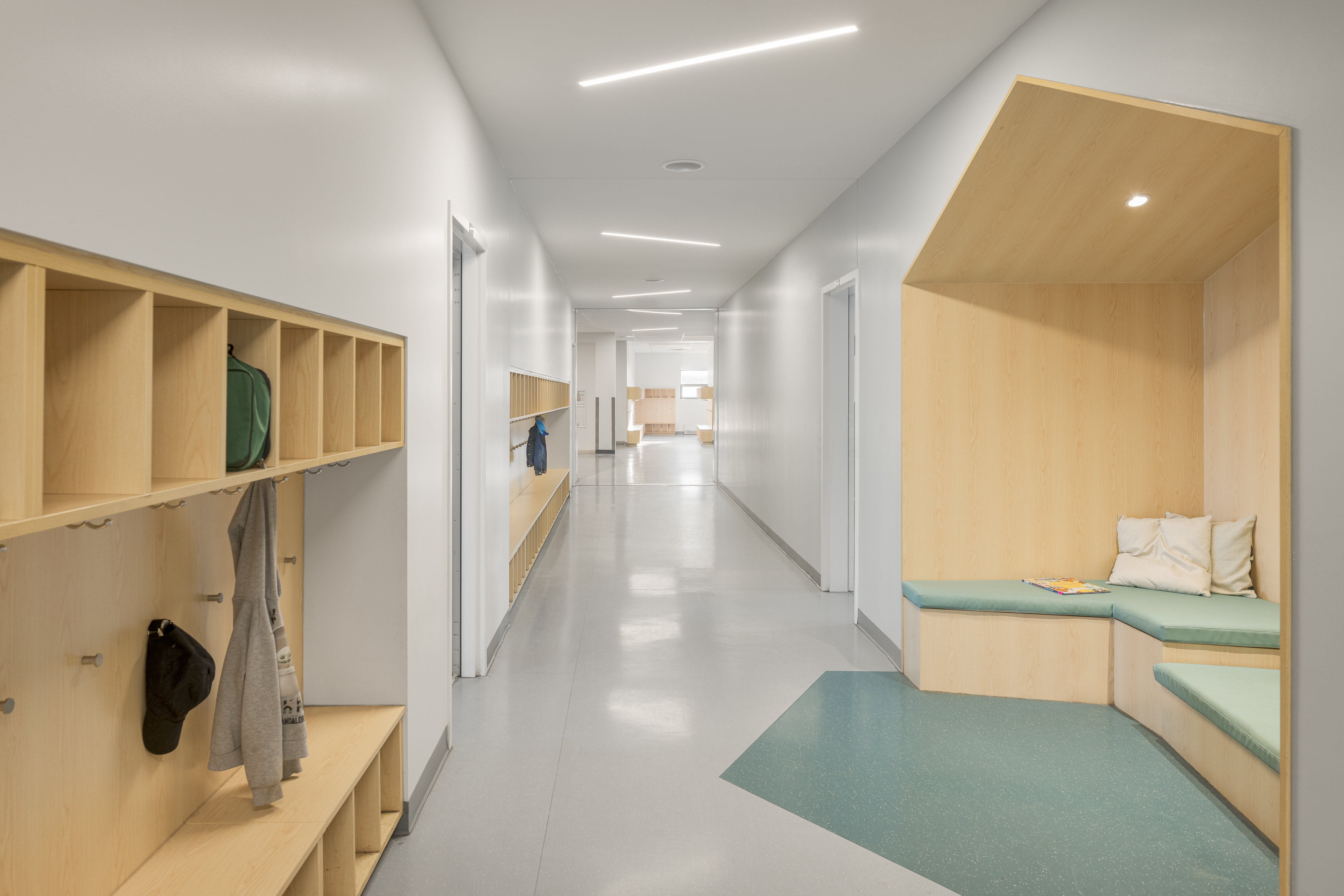 Photographie d’architecture d’un corridor scolaire moderne avec casiers intégrés et design intérieur contemporain.