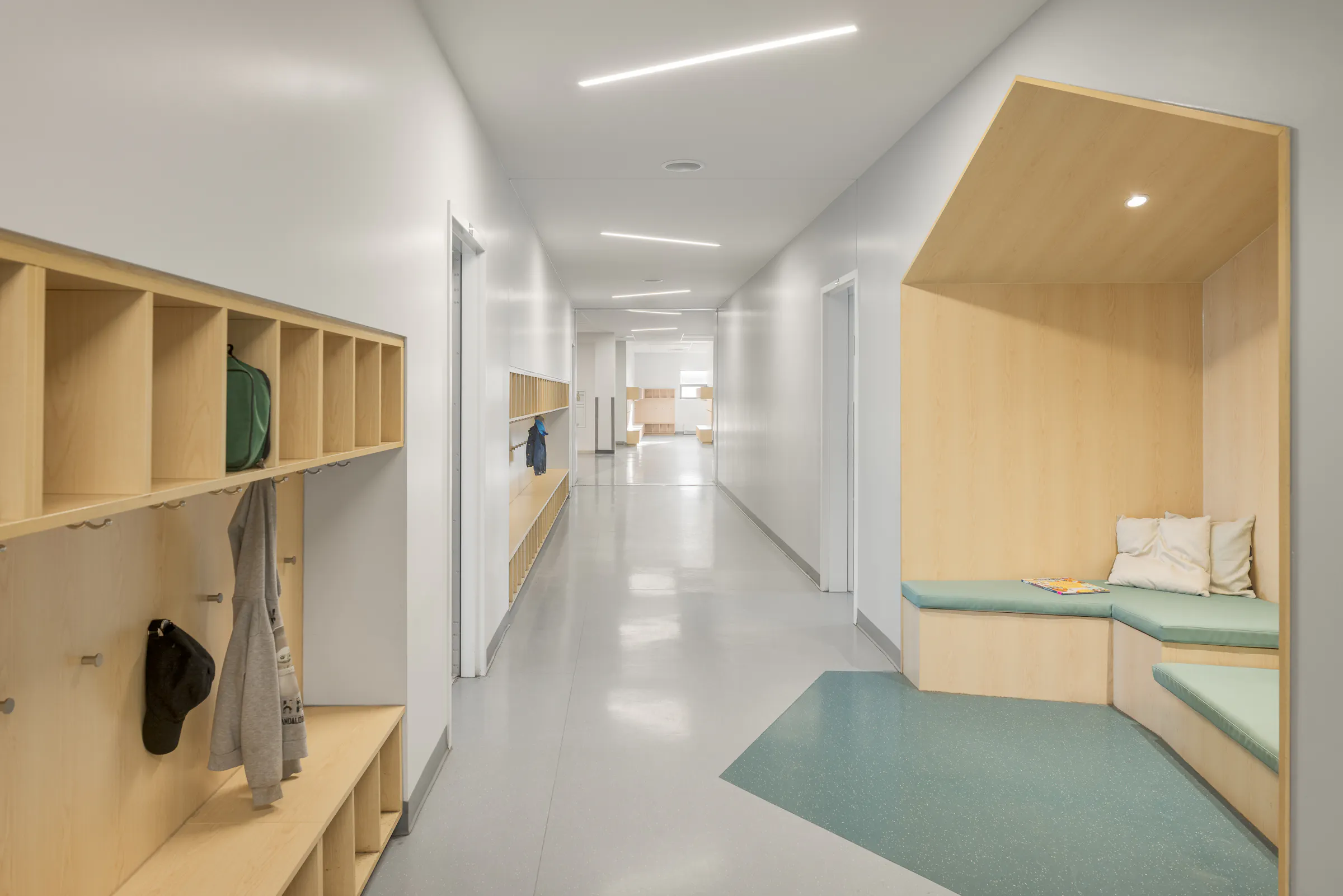 Photographie d’architecture d’un corridor scolaire moderne avec casiers intégrés et design intérieur contemporain.