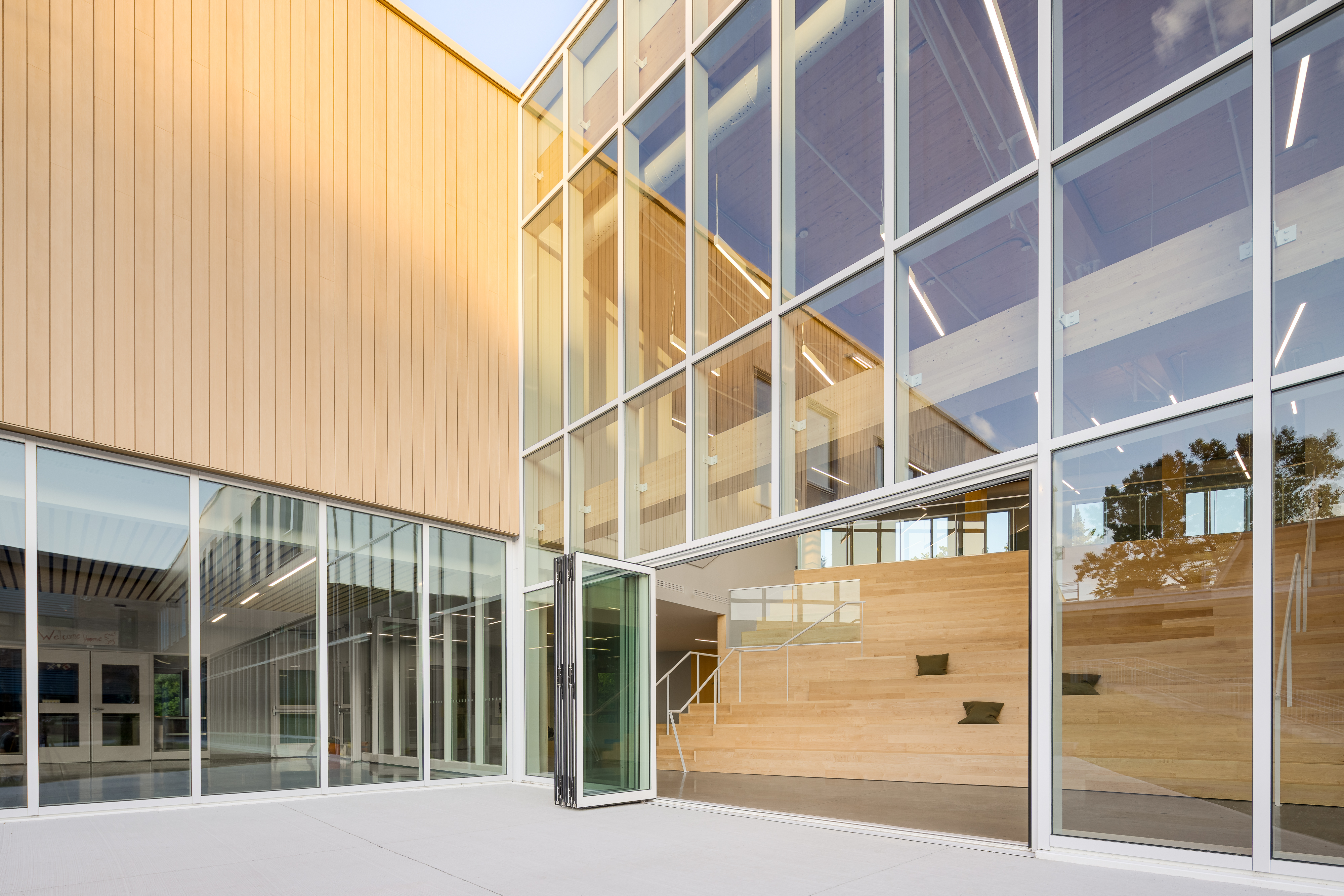 Photographie d’architecture d’une façade d’école contemporaine avec revêtement en bois et cour intérieure.