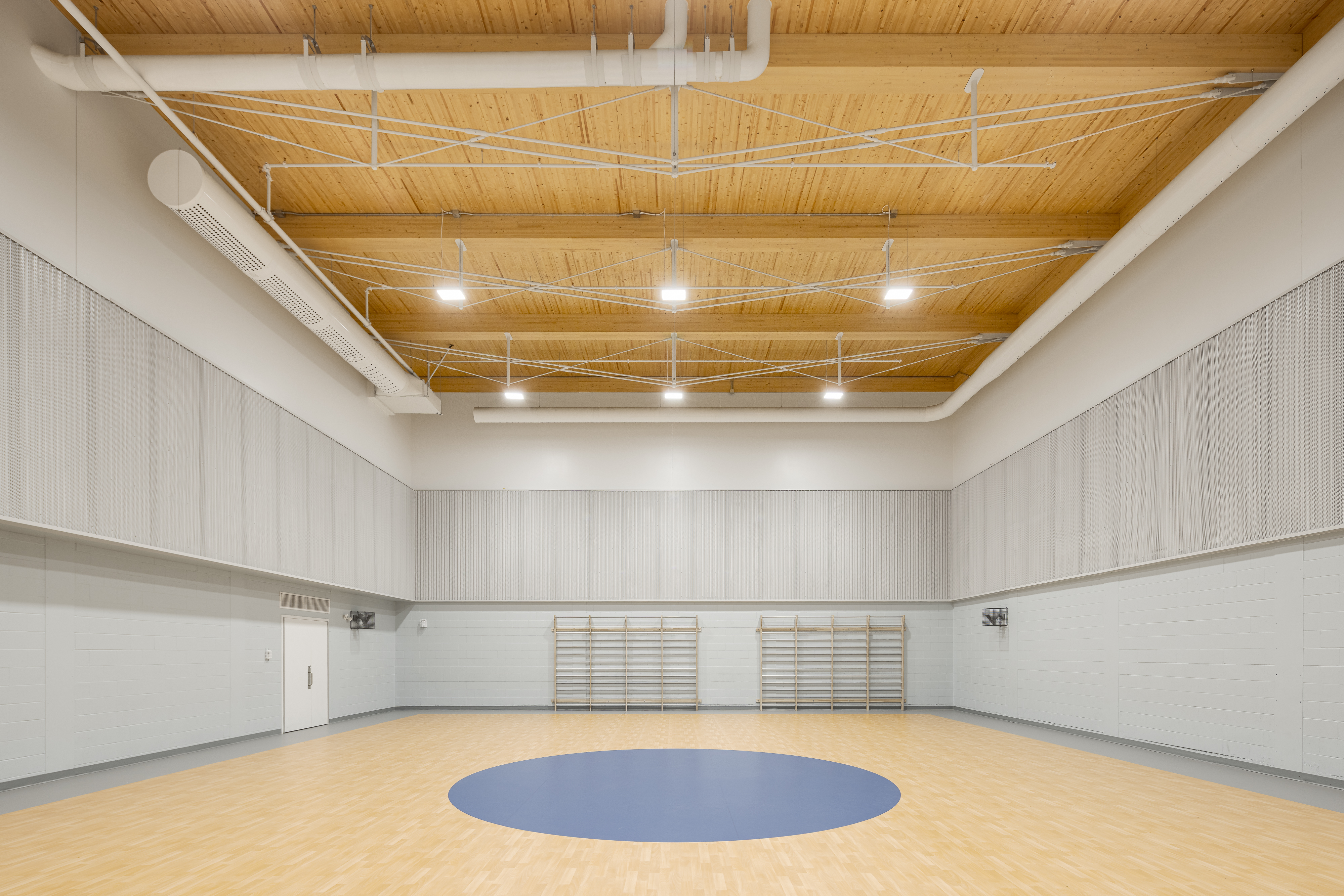 Photographie d’architecture du gymnase d’école contemporaine avec volumes blancs et design moderne.