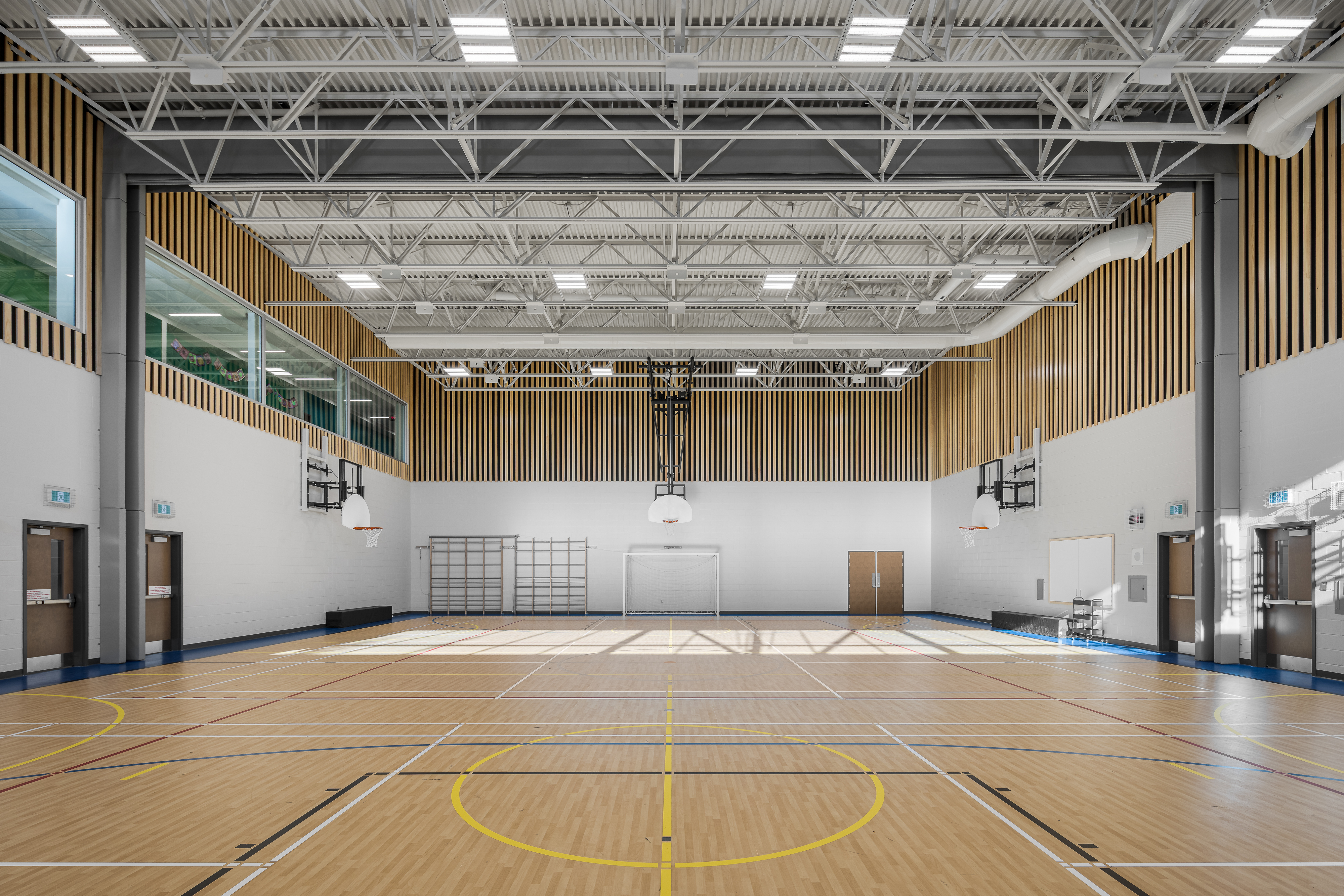 Vue d'ensemble du gymnase double de l'École des Saules, L'Assomption. Finitions bois et toiture industrielle. Photo : Studio Tarmac.
