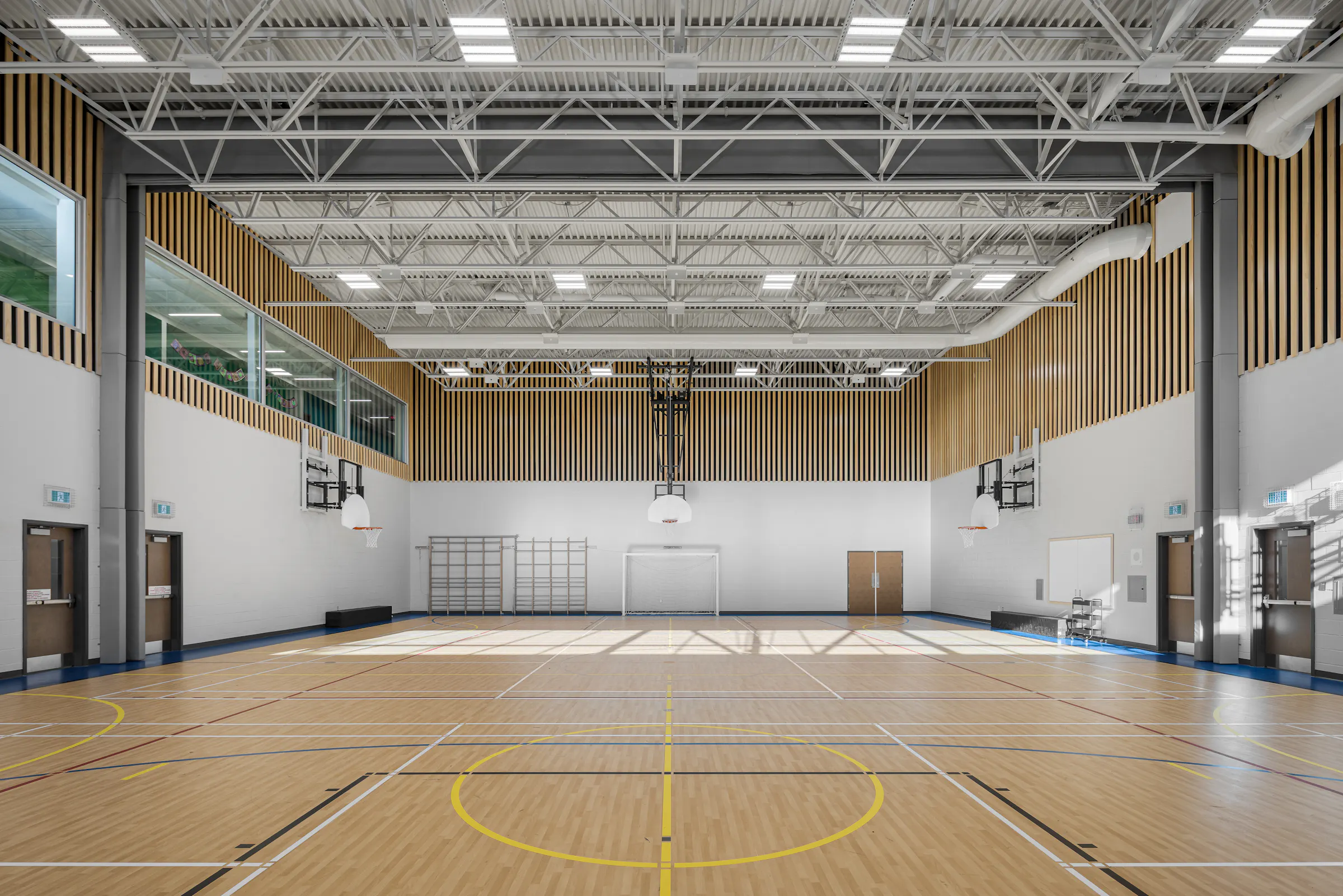 Vue d'ensemble du gymnase double de l'École des Saules, L'Assomption. Finitions bois et toiture industrielle. Photo : Studio Tarmac.