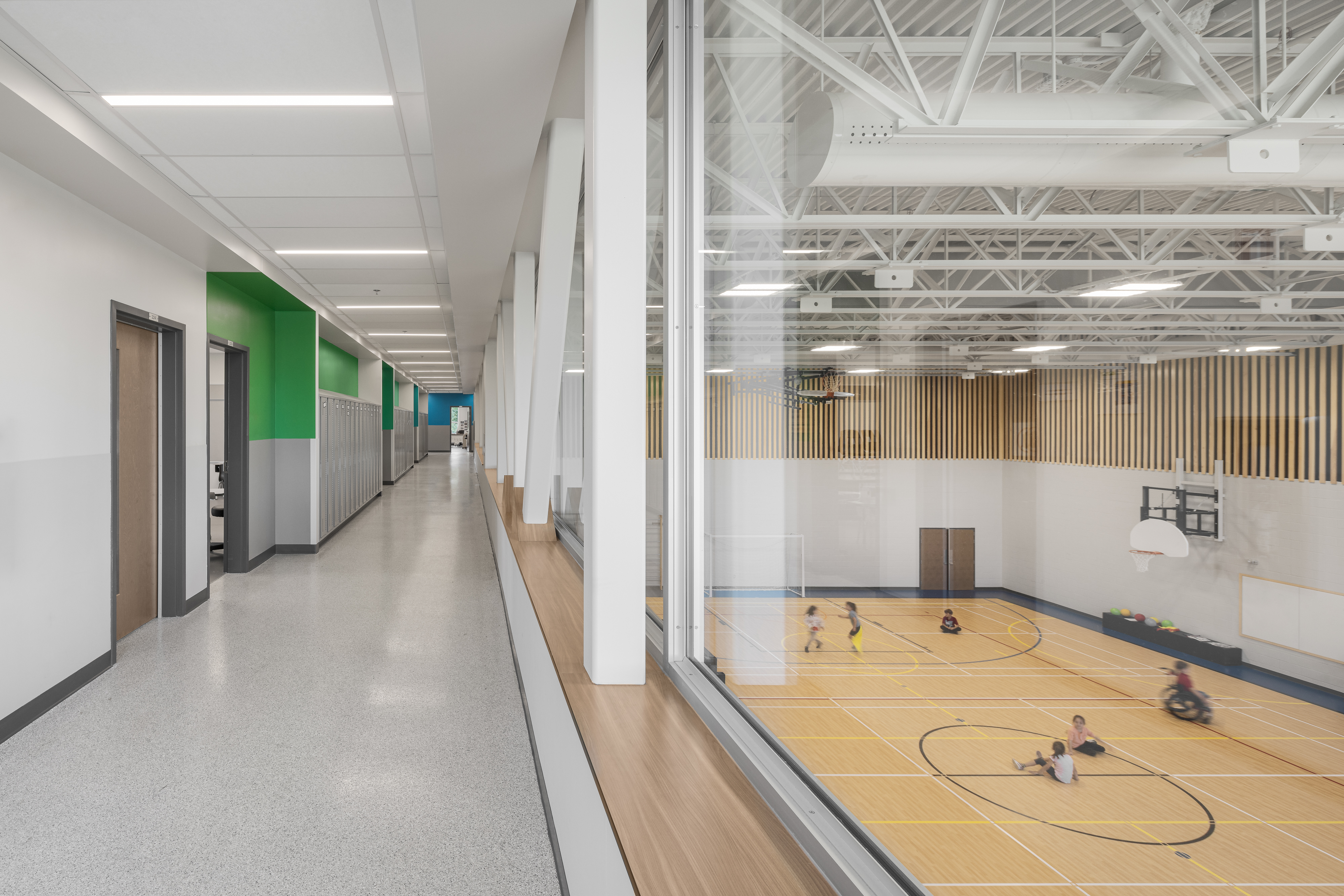 Vue plongeante sur le gymnase double de l'École des Saules, L'Assomption. Boiseries verticales et plancher bois. Photo : Studio Tarmac.