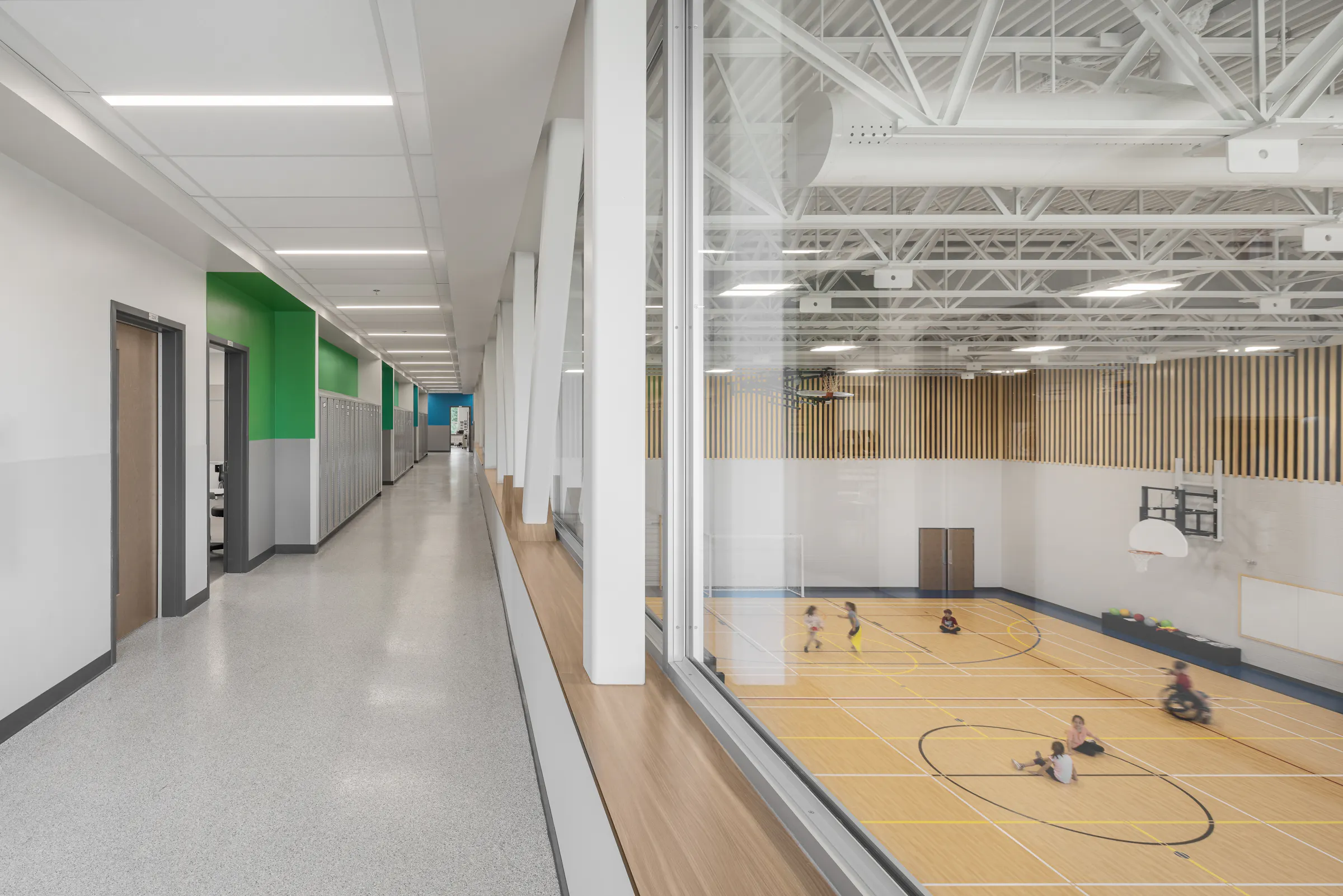Vue plongeante sur le gymnase double de l'École des Saules, L'Assomption. Boiseries verticales et plancher bois. Photo : Studio Tarmac.