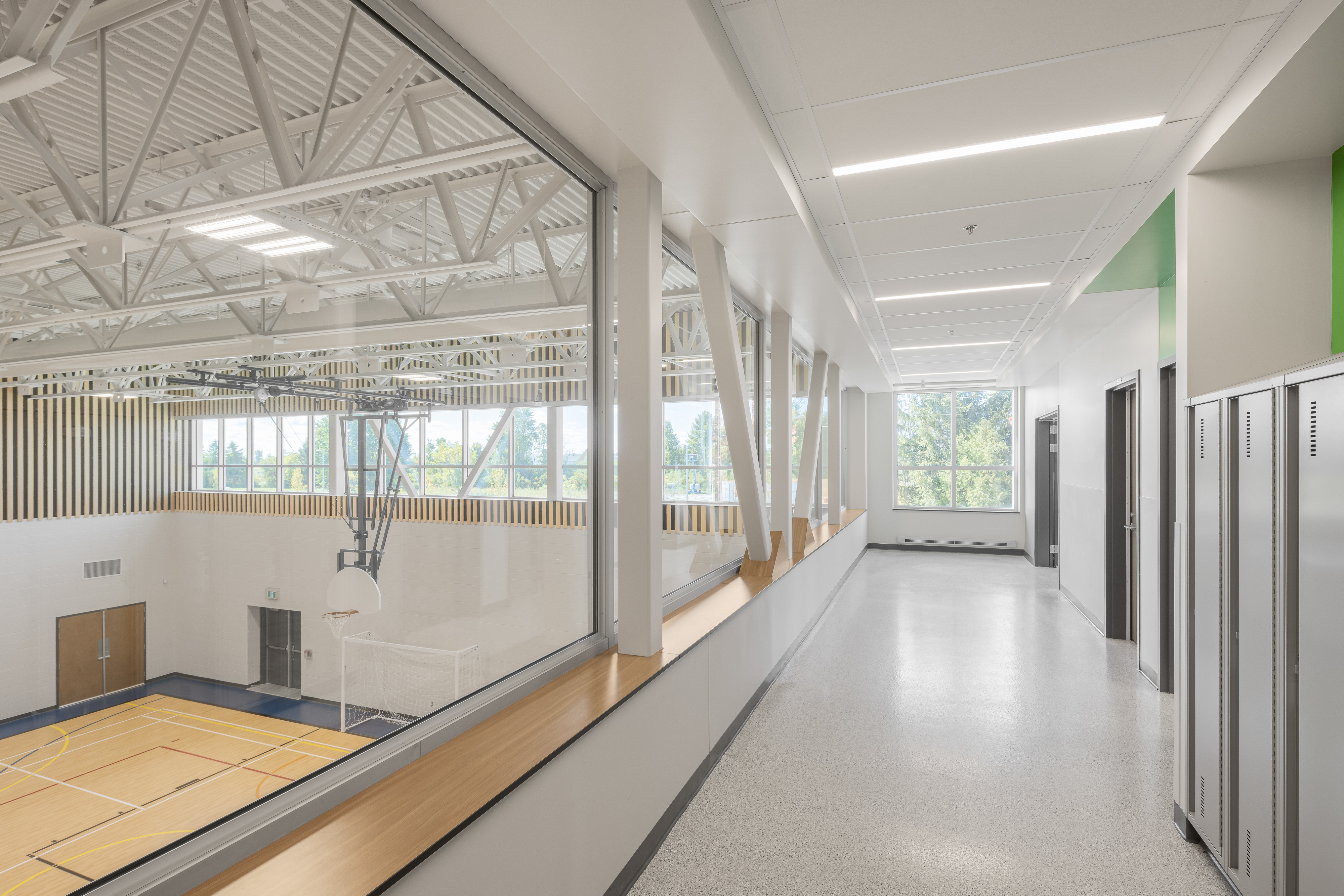 Corridor vitré à l'étage avec vue sur le gymnase de l'École des Saules, L'Assomption. Architecture Bergeron Bouthillier. Photo : Studio Tarmac.