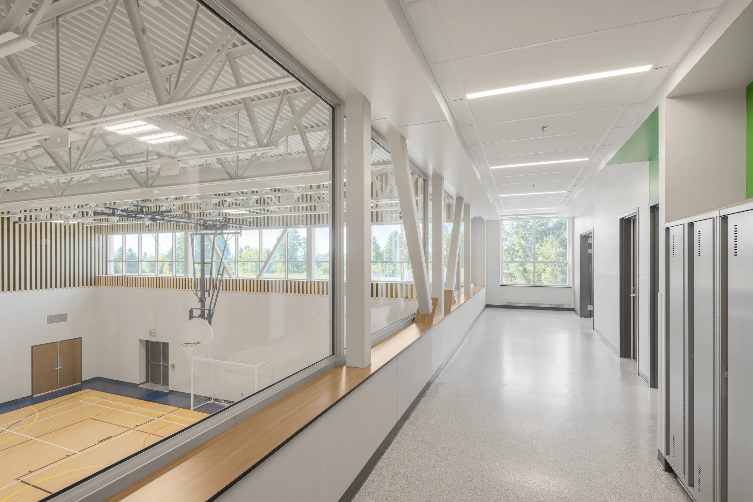 Corridor vitré à l'étage avec vue sur le gymnase de l'École des Saules, L'Assomption. Architecture Bergeron Bouthillier. Photo : Studio Tarmac.