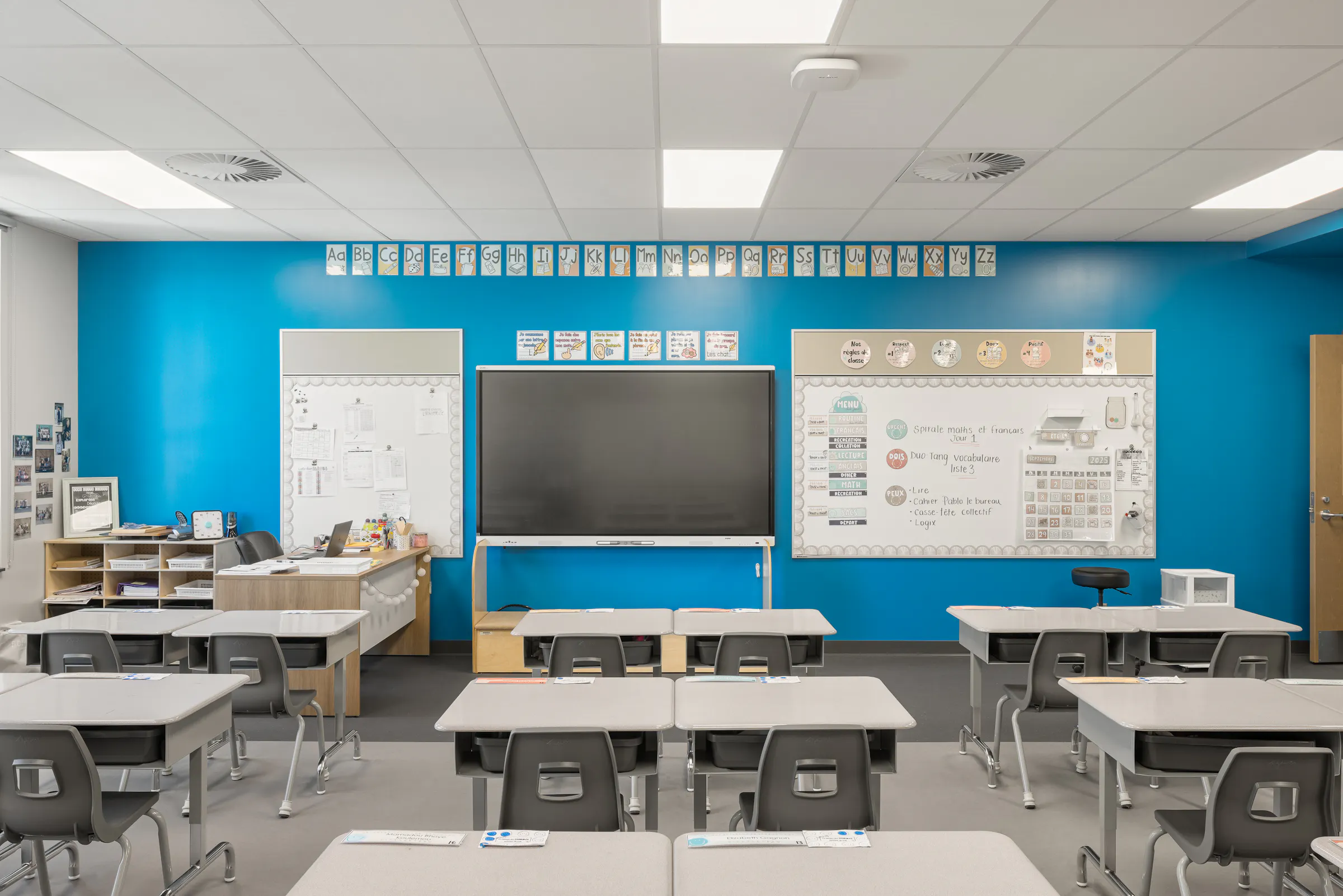 Salle de classe de l'École des Saules, L'Assomption. Mur bleu, mobilier modulable et lumière naturelle. Photo : Studio Tarmac.