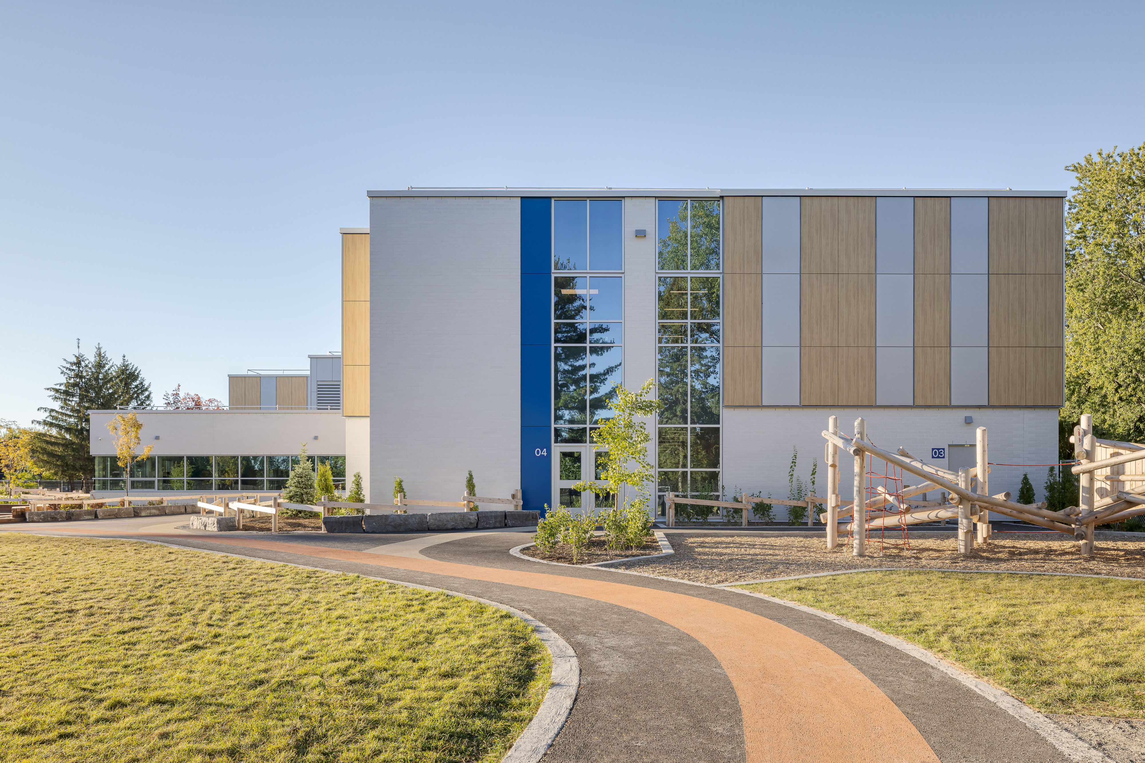 Entrée de l'École des Saules, L'Assomption avec mât de drapeau. Matériaux contemporains et accents bleu fleurdelisé. Photo : TARMAC - Damien Ligiardi.