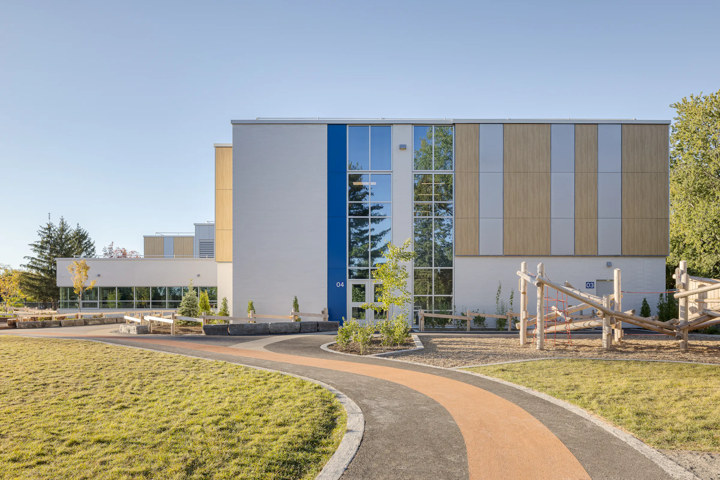 Entrée de l'École des Saules, L'Assomption avec mât de drapeau. Matériaux contemporains et accents bleu fleurdelisé. Photo : TARMAC - Damien Ligiardi.