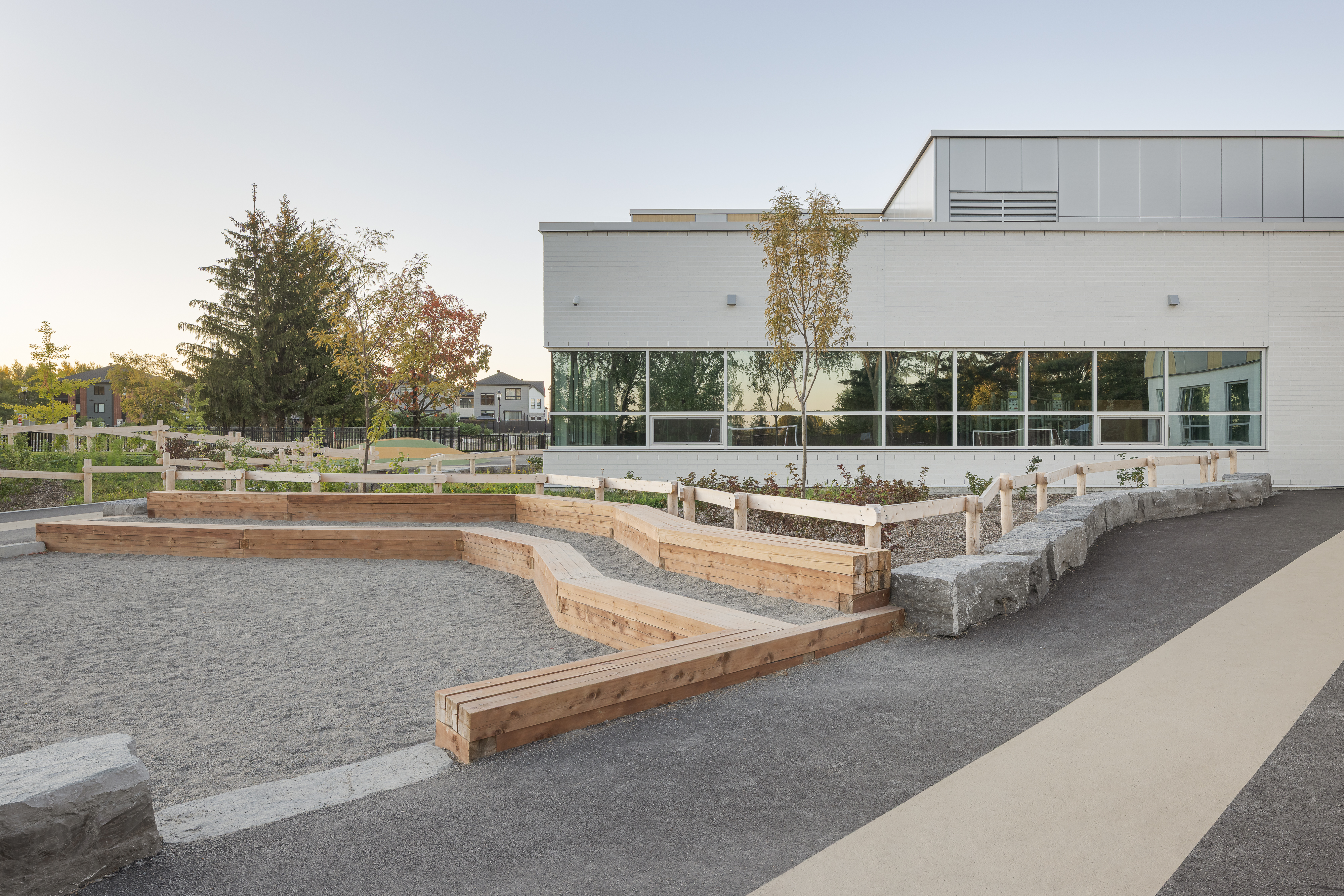 Aménagements extérieurs en gradins de l'École des Saules, L'Assomption. Murets de bois et espaces de jeu intégrés. Photo : TARMAC - Damien Ligiardi.
