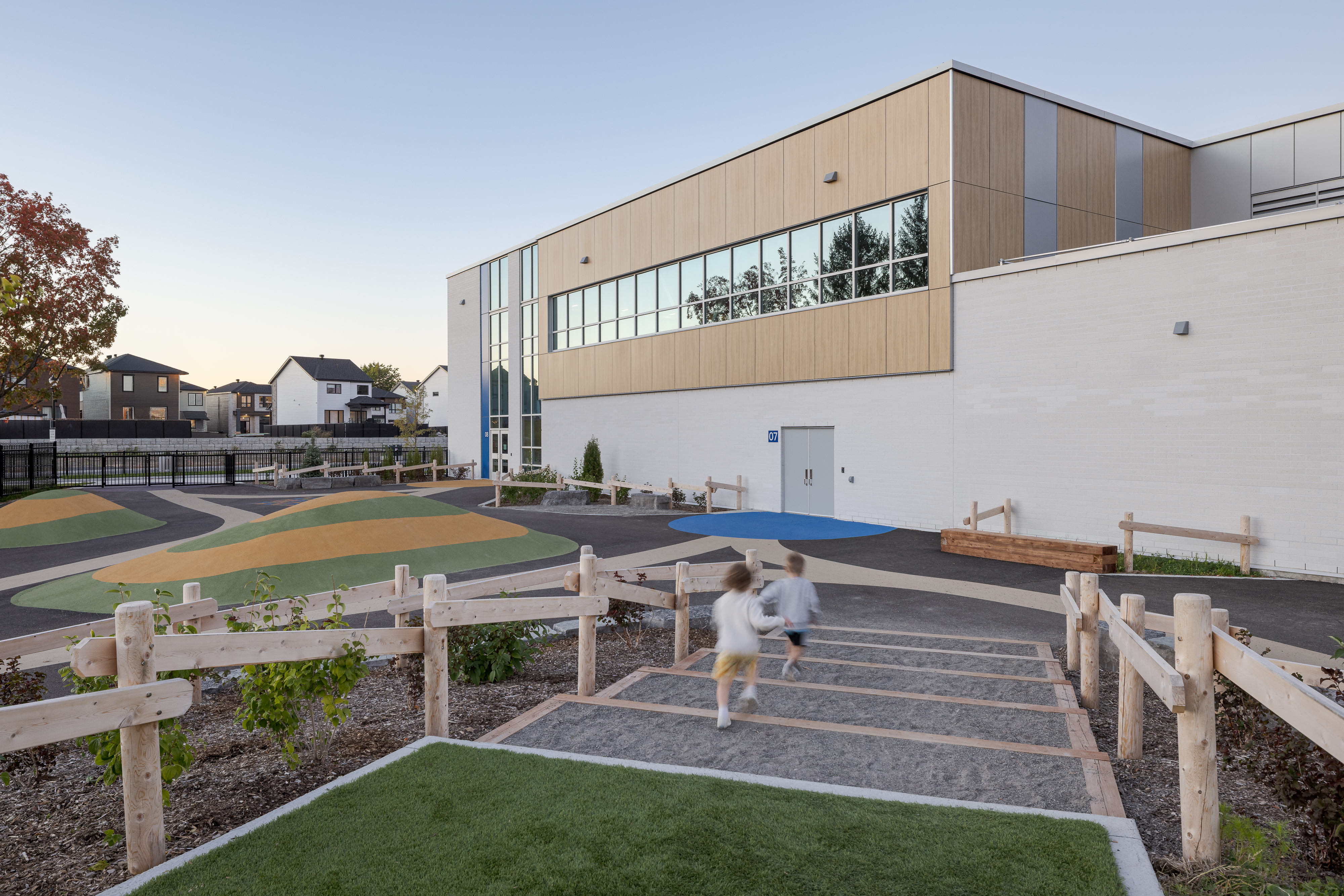 Cour de l'École des Saules, L'Assomption avec escaliers en bois et élève. Architecture scolaire contemporaine québécoise. Photo : TARMAC - Damien Ligiardi.