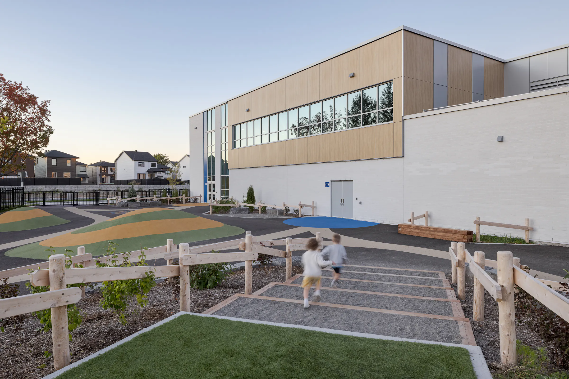 Cour de l'École des Saules, L'Assomption avec escaliers en bois et élève. Architecture scolaire contemporaine québécoise. Photo : TARMAC - Damien Ligiardi.