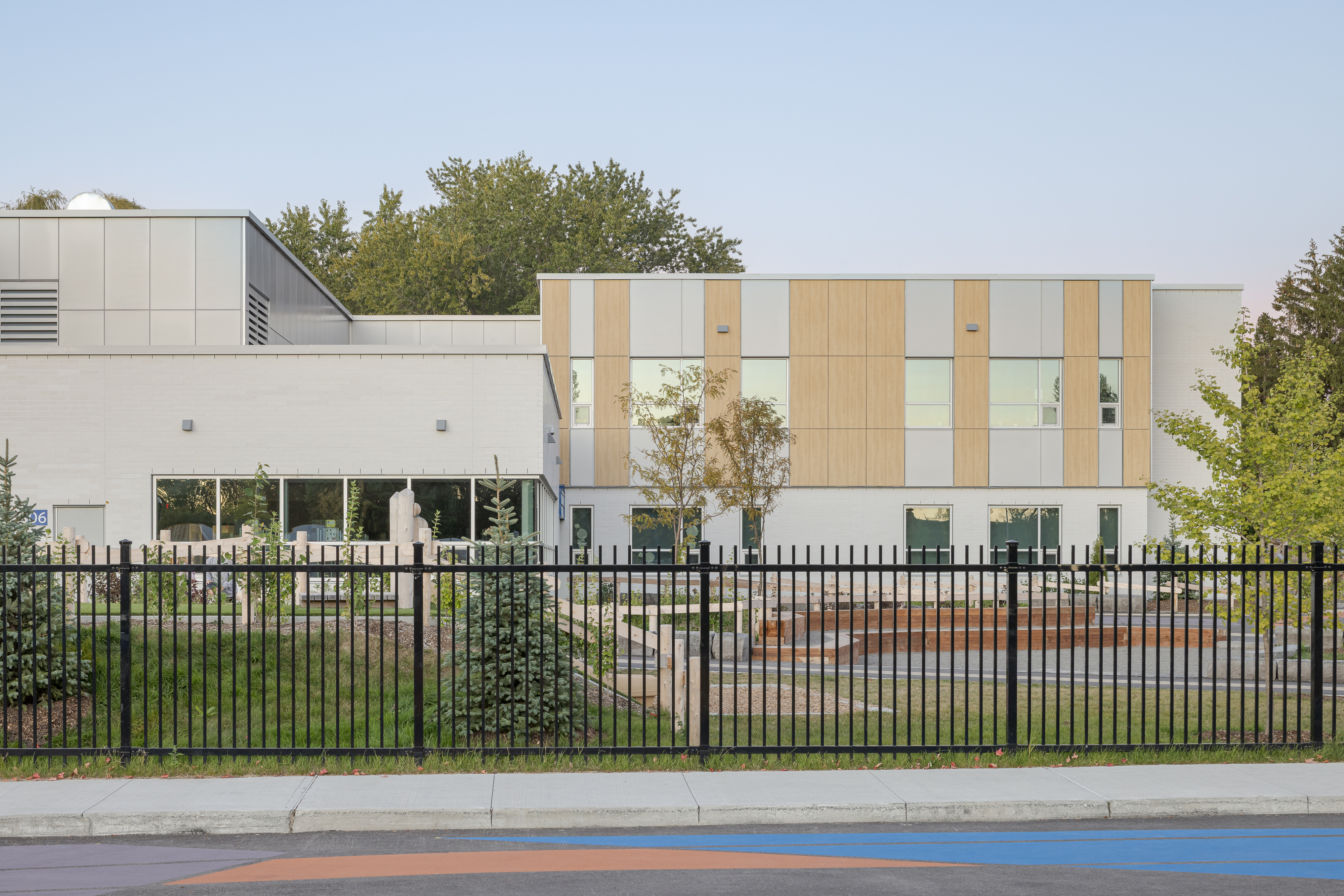 Façade arrière de l'École des Saules, L'Assomption vue depuis la clôture. Volumes contrastés et végétation environnante. Photo : TARMAC - Damien Ligiardi.