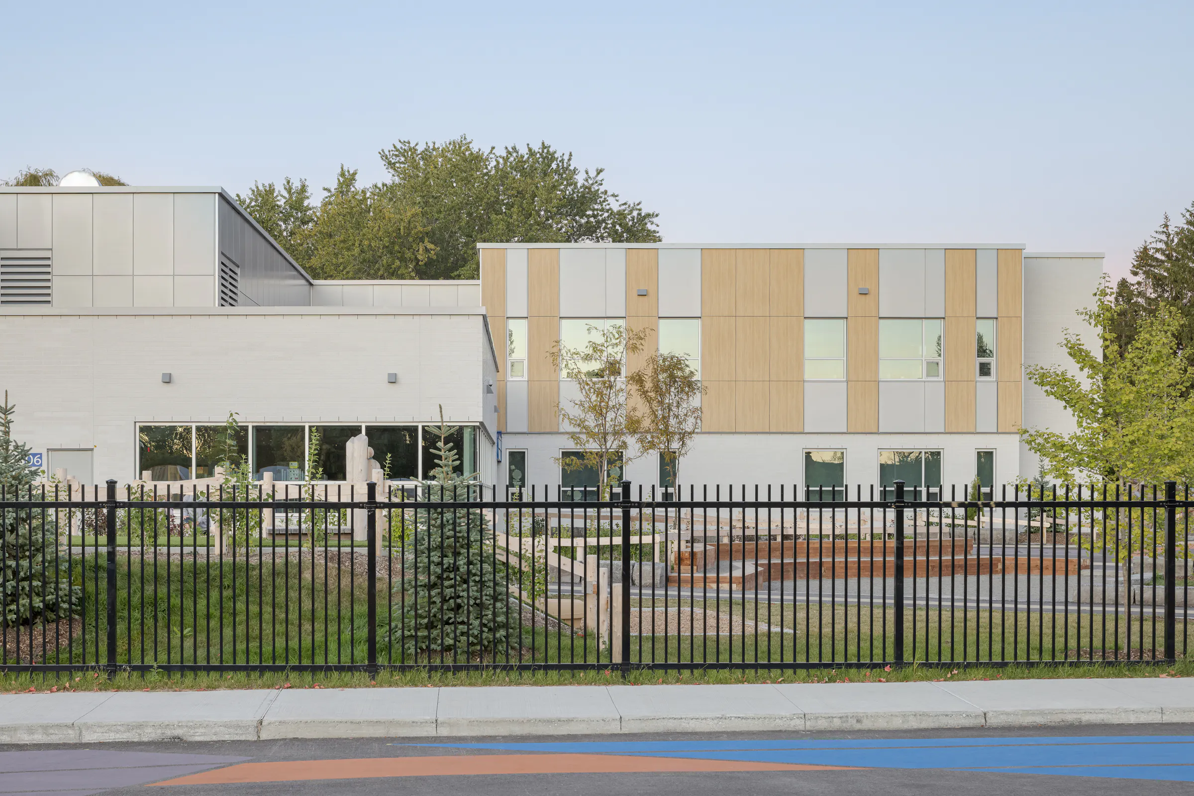 Façade arrière de l'École des Saules, L'Assomption vue depuis la clôture. Volumes contrastés et végétation environnante. Photo : TARMAC - Damien Ligiardi.