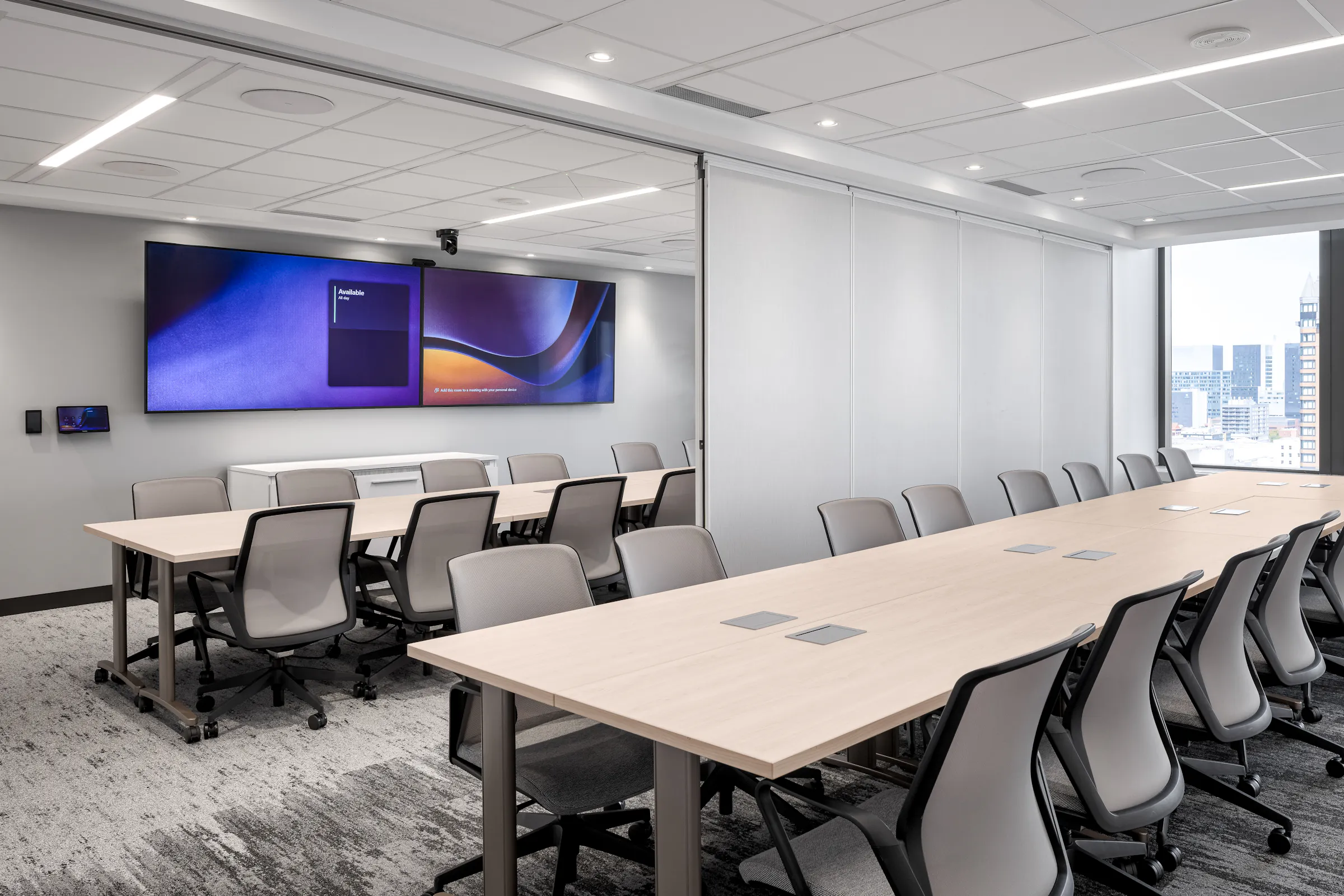 Grande salle de conférence avec table allongée, chaises ergonomiques grises et oeuvre murale aux tons violets, bureaux d'Airport Council International, Montréal. Photo : TARMAC - Damien Ligiardi