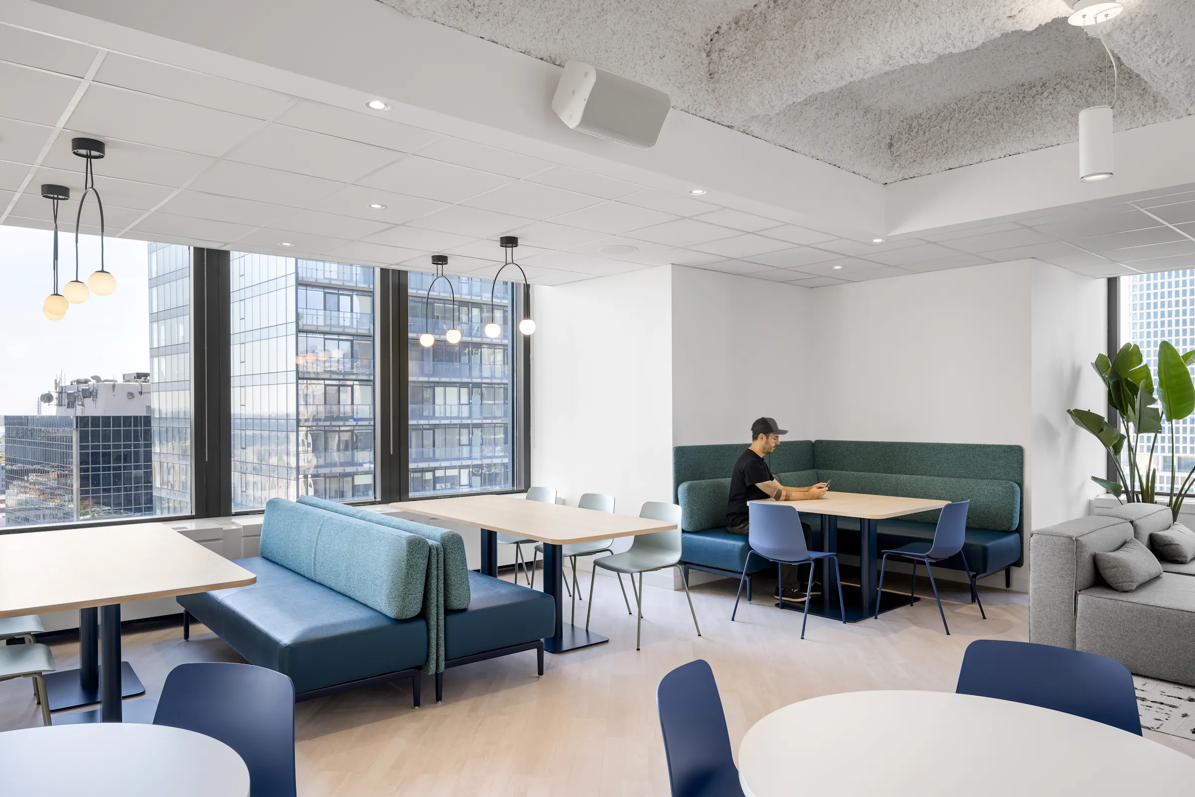 Zone de collaboration ouverte avec canapés bleus et banquettes modulaires, dans les nouveaux bureaux d'Airport Council International à la Place Victoria. Photo : TARMAC - Damien Ligiardi