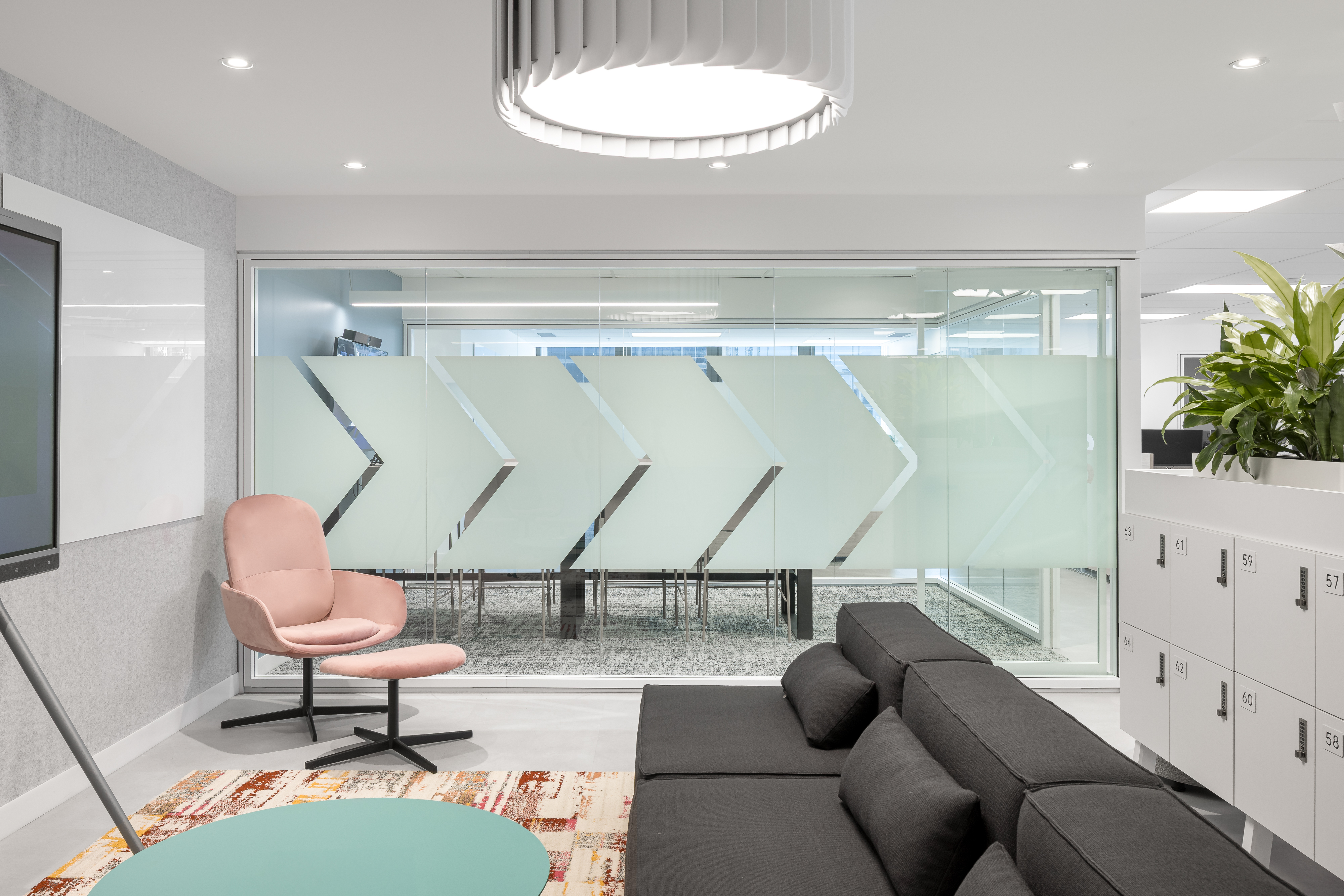 Espace de collaboration avec écran mural, mobilier clair et plantes vertes, bureaux d'ACI World à Montréal, design intérieur Conceptum International. Photo : TARMAC - Damien Ligiardi