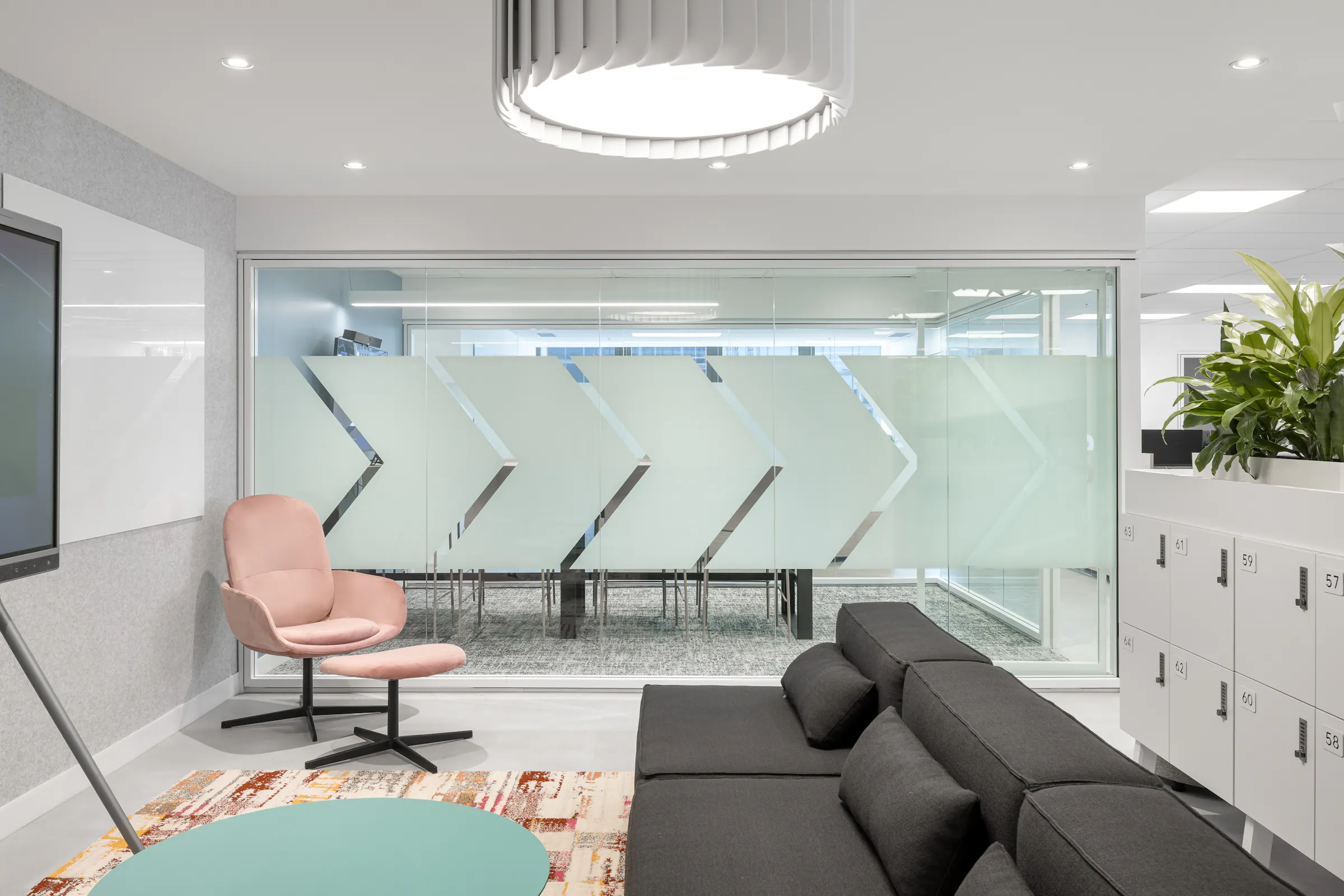 Espace de collaboration avec écran mural, mobilier clair et plantes vertes, bureaux d'ACI World à Montréal, design intérieur Conceptum International. Photo : TARMAC - Damien Ligiardi