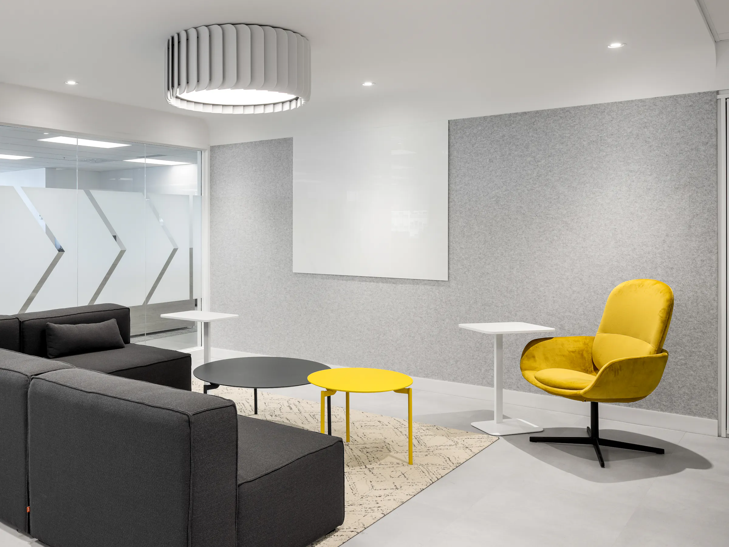 Salon de détente avec canapé gris et fauteuils jaunes, espace de collaboration informelle dans les bureaux d'ACI World à la Place Victoria. Photo : TARMAC - Damien Ligiardi