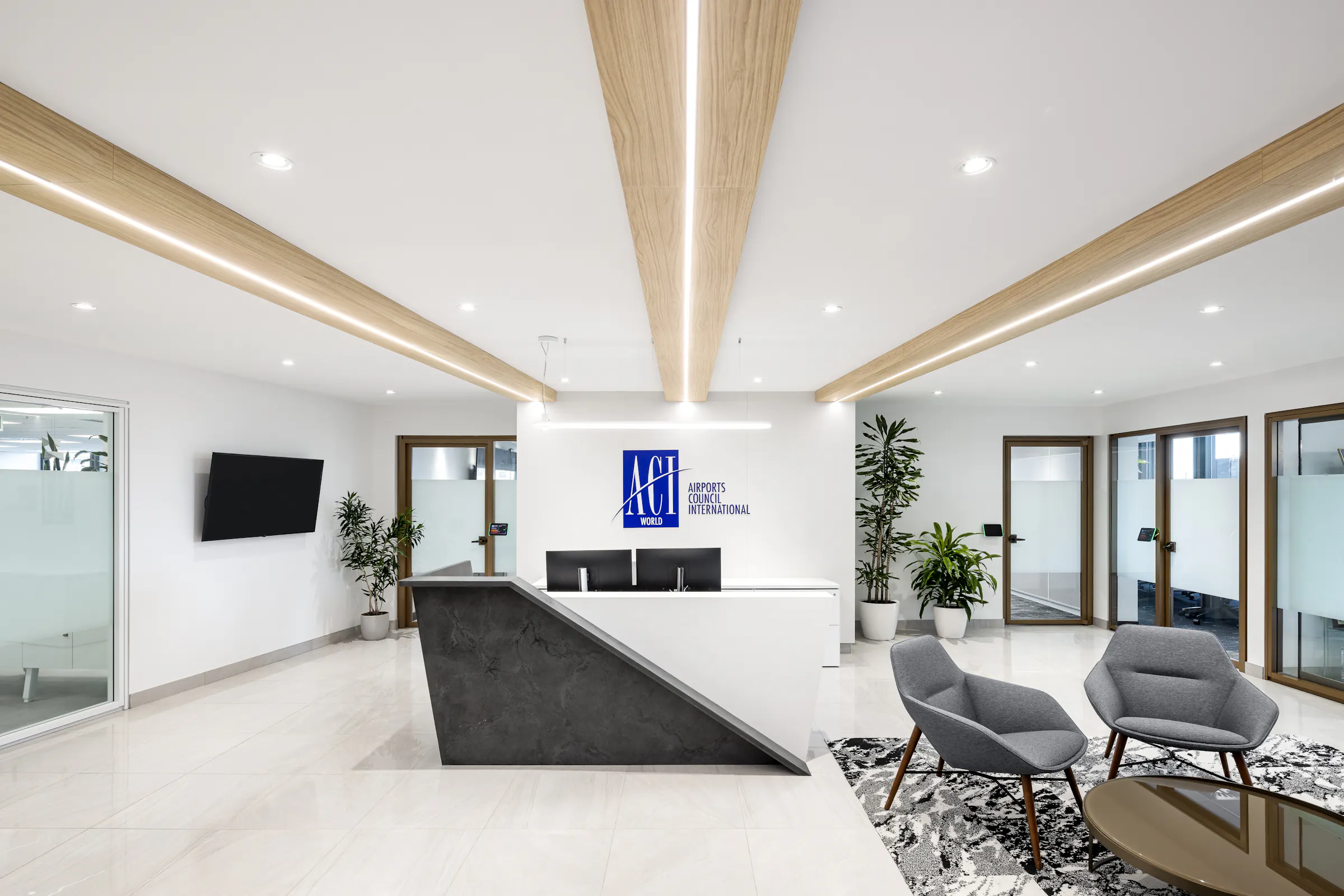 Couloir d'accueil avec poutres en ébénisterie rappelant la cabine d'avion, menant à la réception des bureaux d'ACI World, Montréal. Photo : TARMAC - Damien Ligiardi