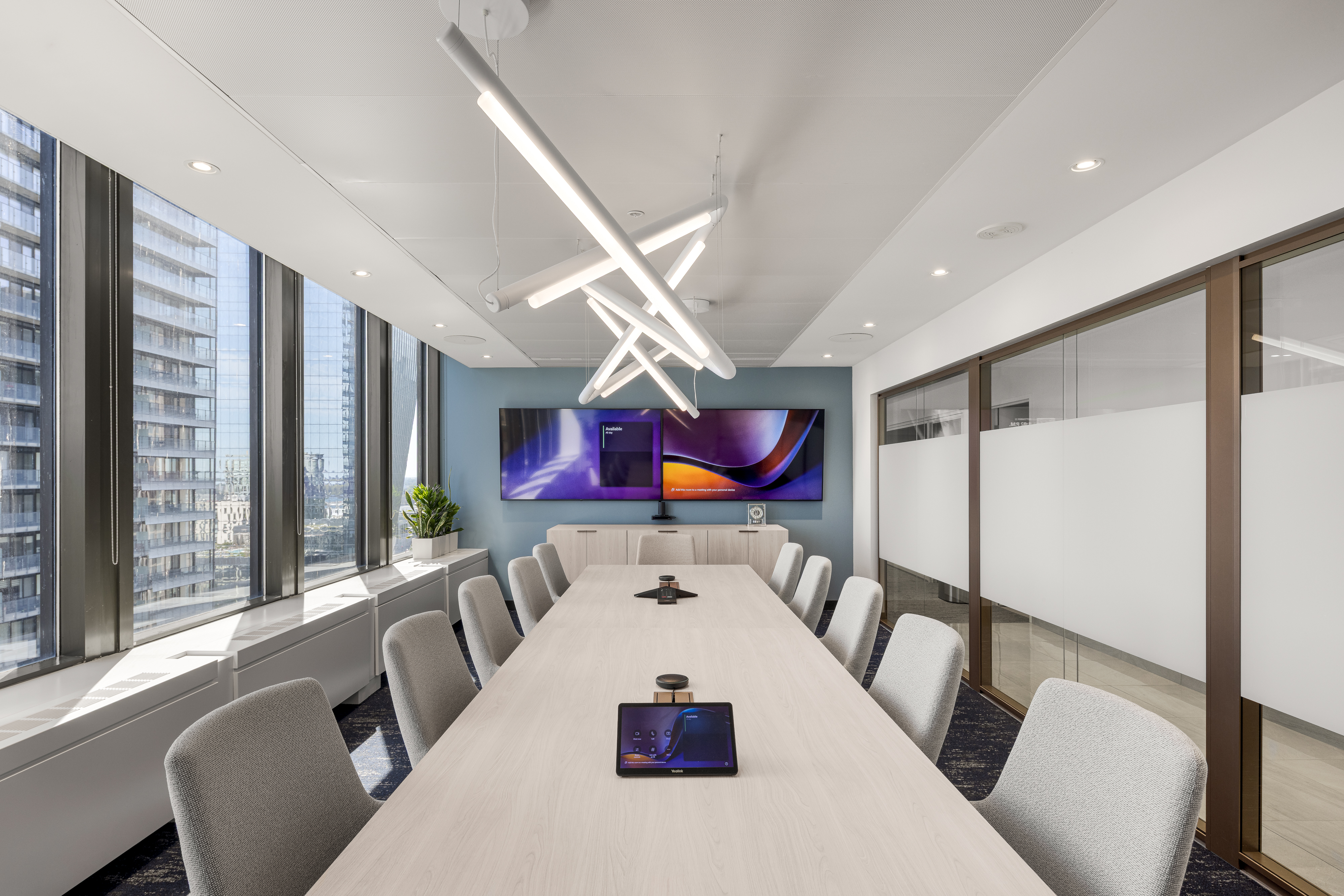 Grande salle de conférence avec longue table blanche et chaises grises, art mural abstrait aux tons violets et bleus, bureaux ACI World. Photo : TARMAC - Damien Ligiardi