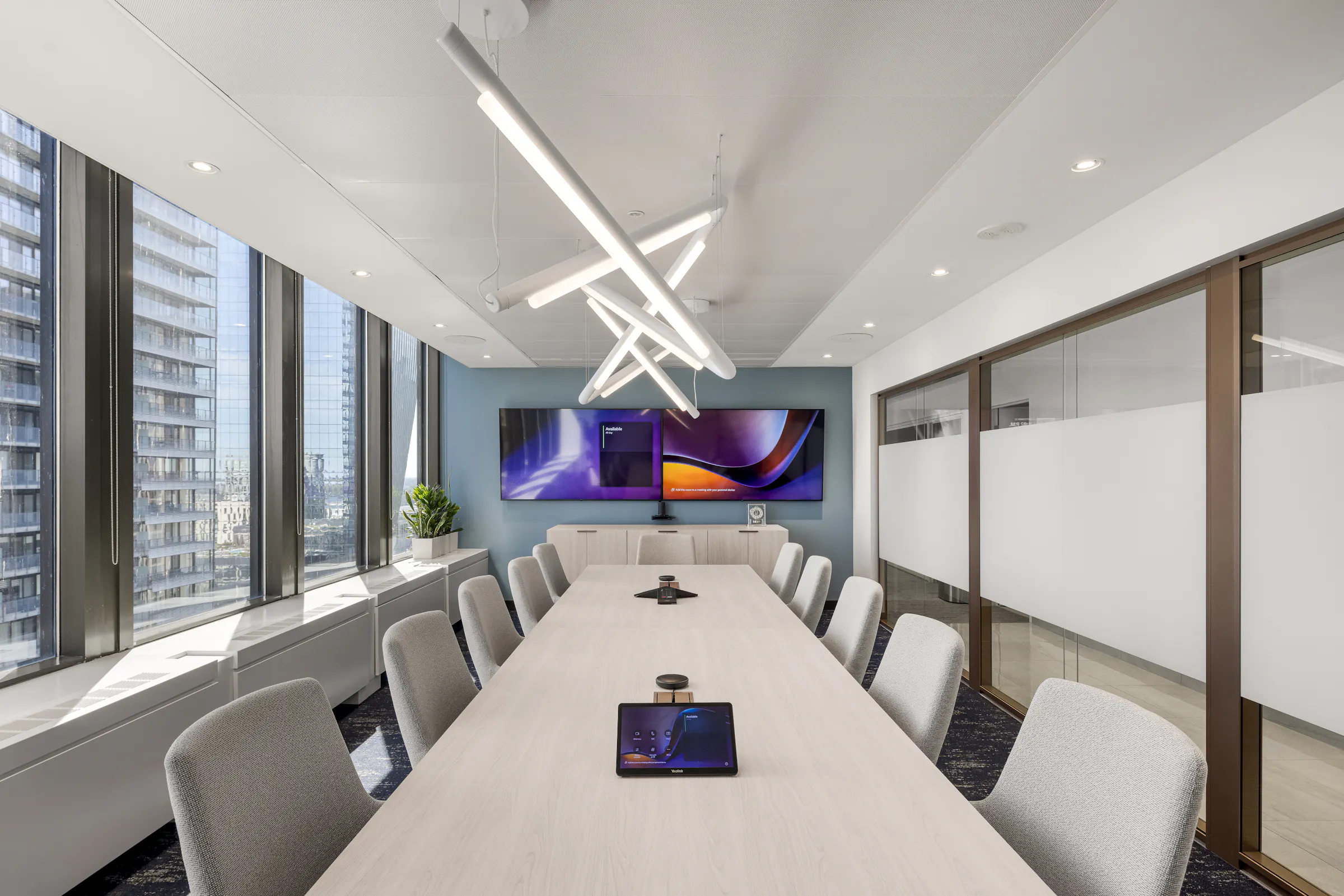Grande salle de conférence avec longue table blanche et chaises grises, art mural abstrait aux tons violets et bleus, bureaux ACI World. Photo : TARMAC - Damien Ligiardi