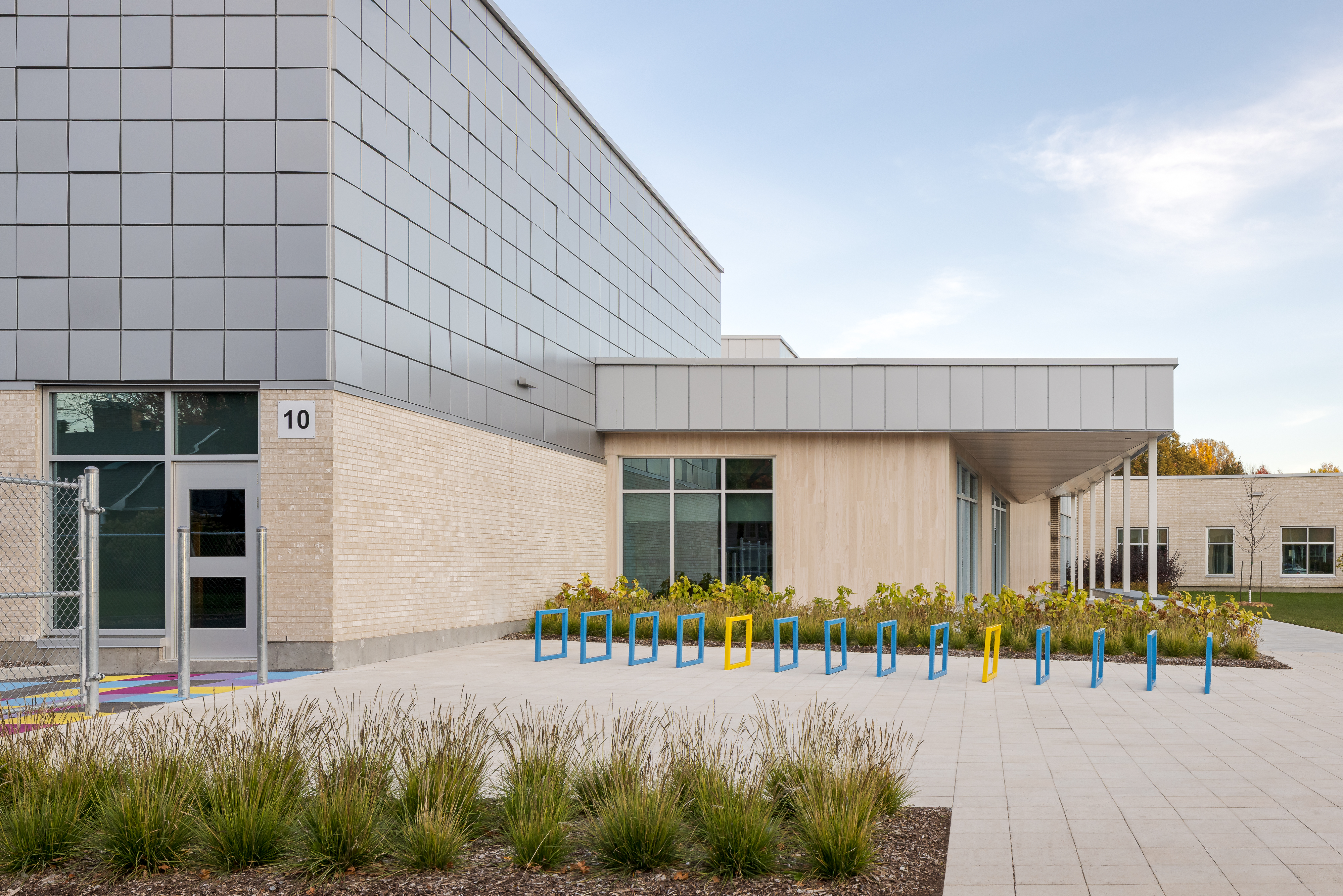 Redesigned playground with bicycle racks, covered outdoor wooden structure, and green spaces. Photo: TARMAC - Damien Ligiardi