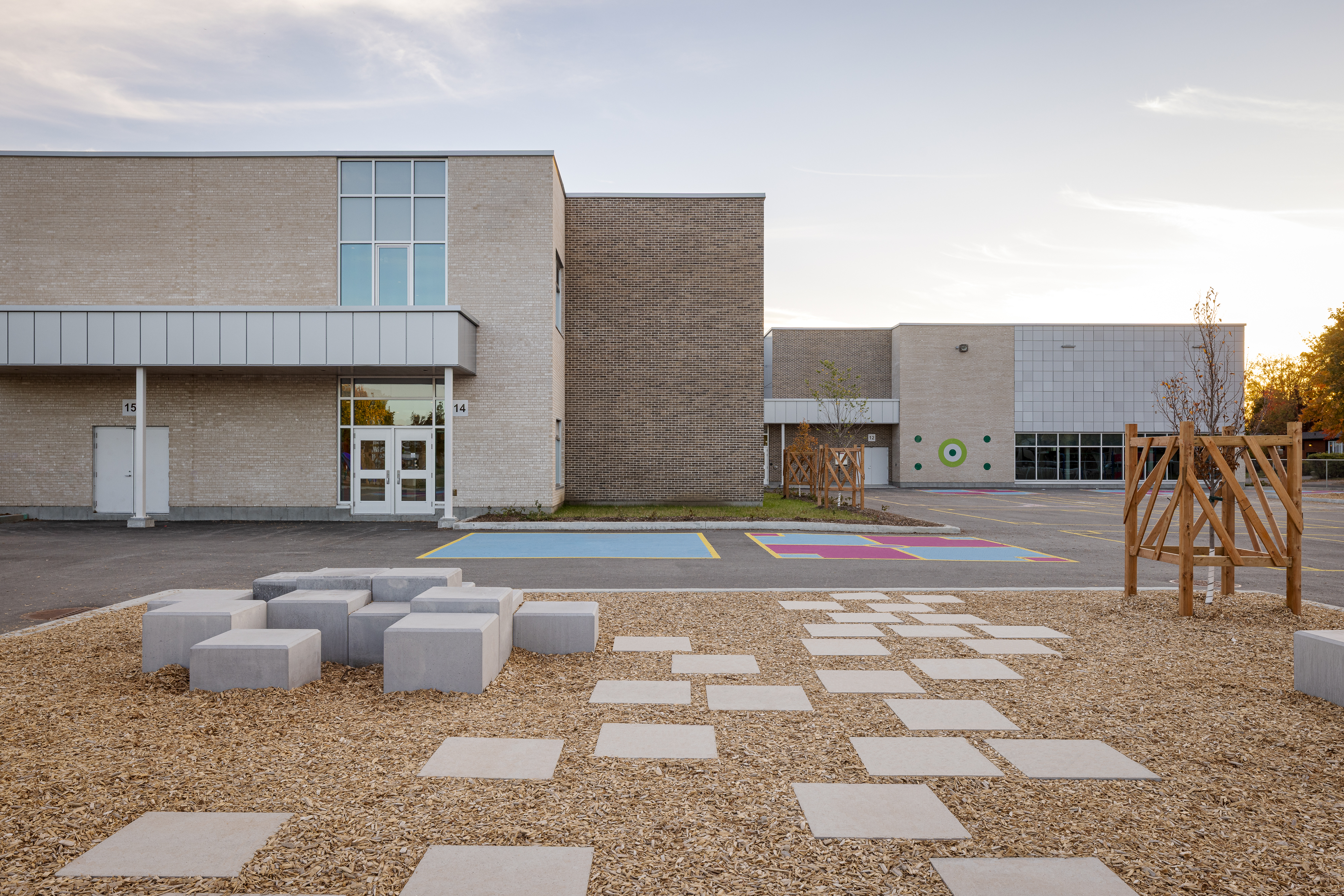 Playground with concrete street furniture and landscaping, school facade in the background. Photo: TARMAC - Damien Ligiardi