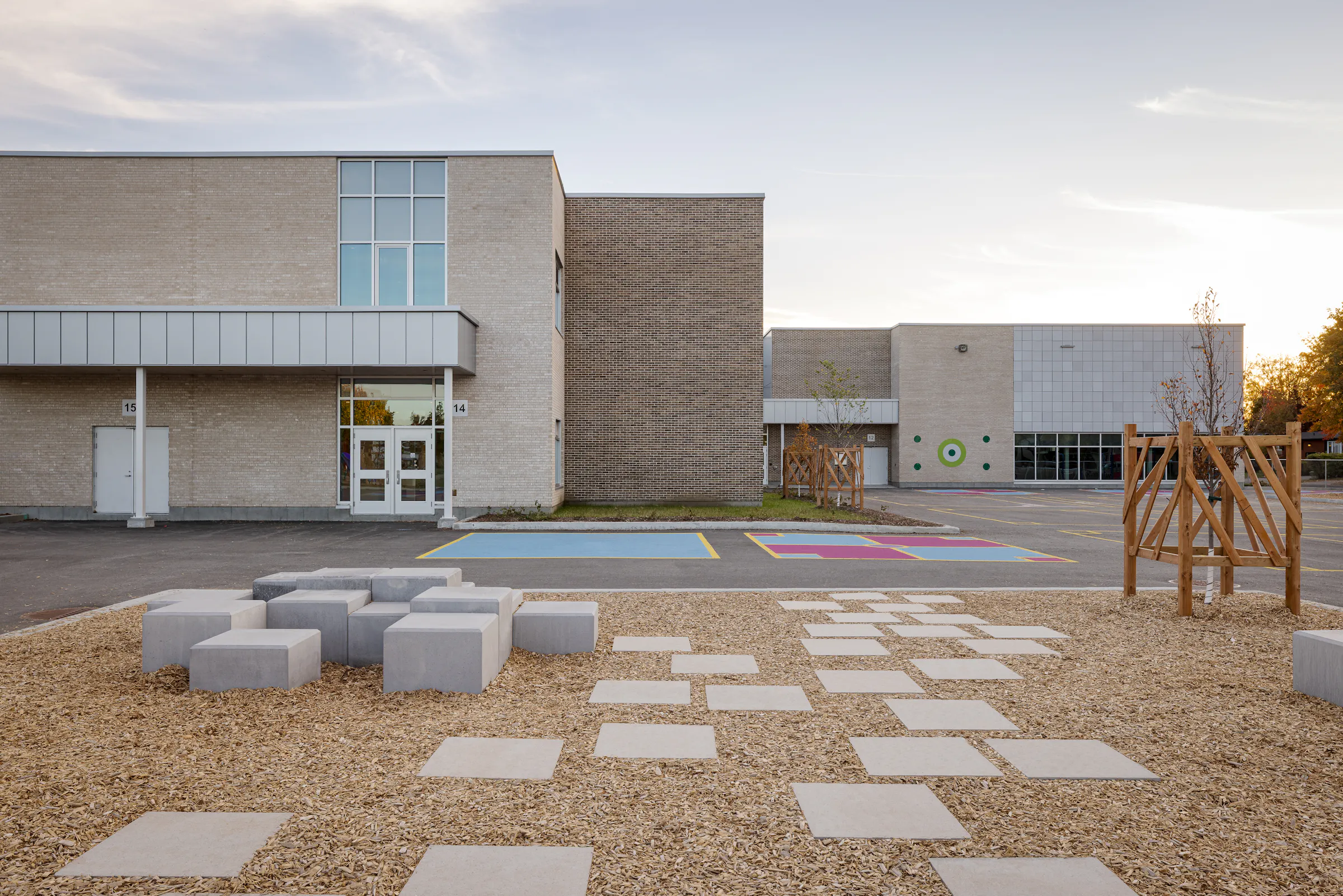 Playground with concrete street furniture and landscaping, school facade in the background. Photo: TARMAC - Damien Ligiardi