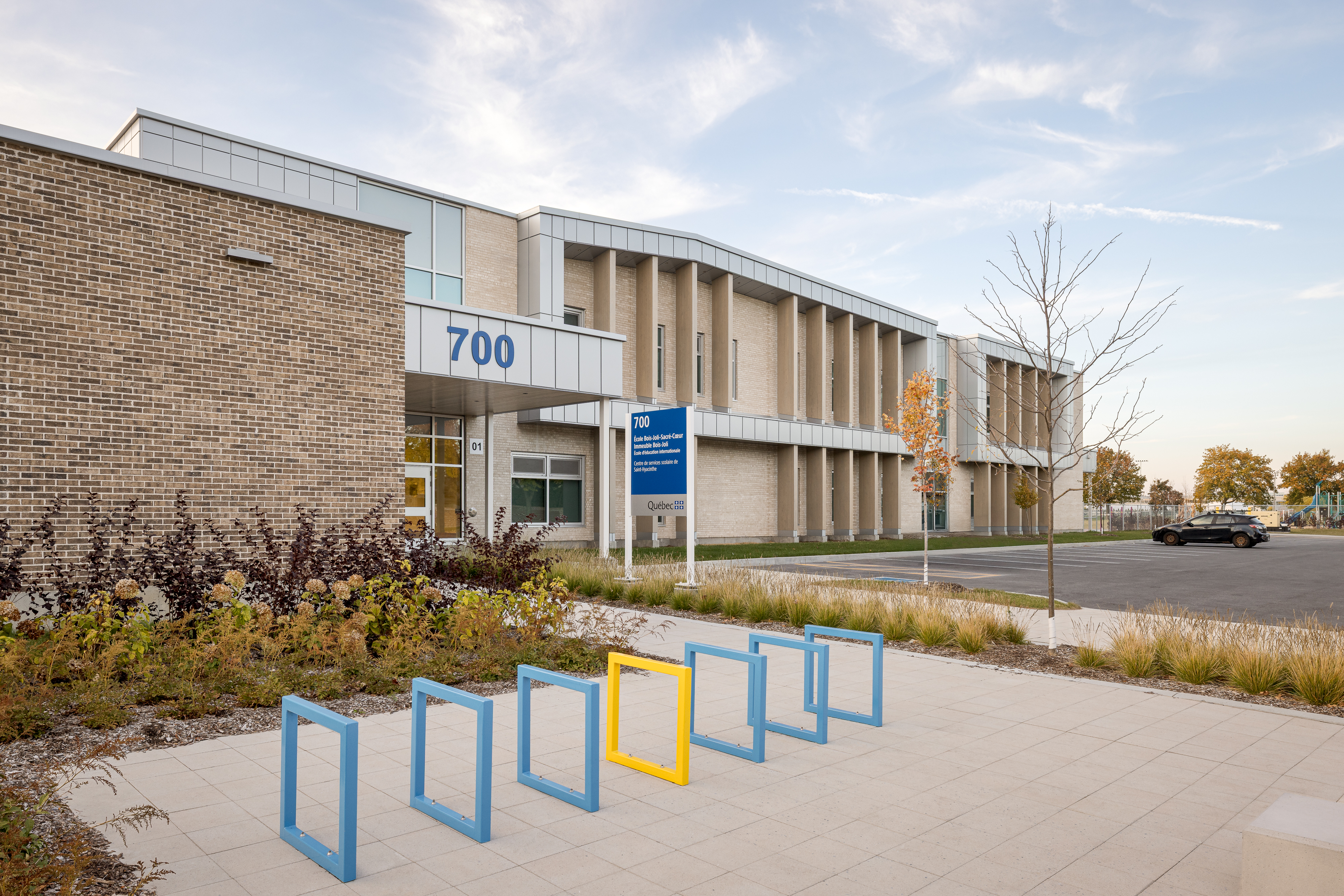 Facade overlooking the courtyard, secondary entrance with signage and colorful bicycle racks. Photo: TARMAC - Damien Ligiardi