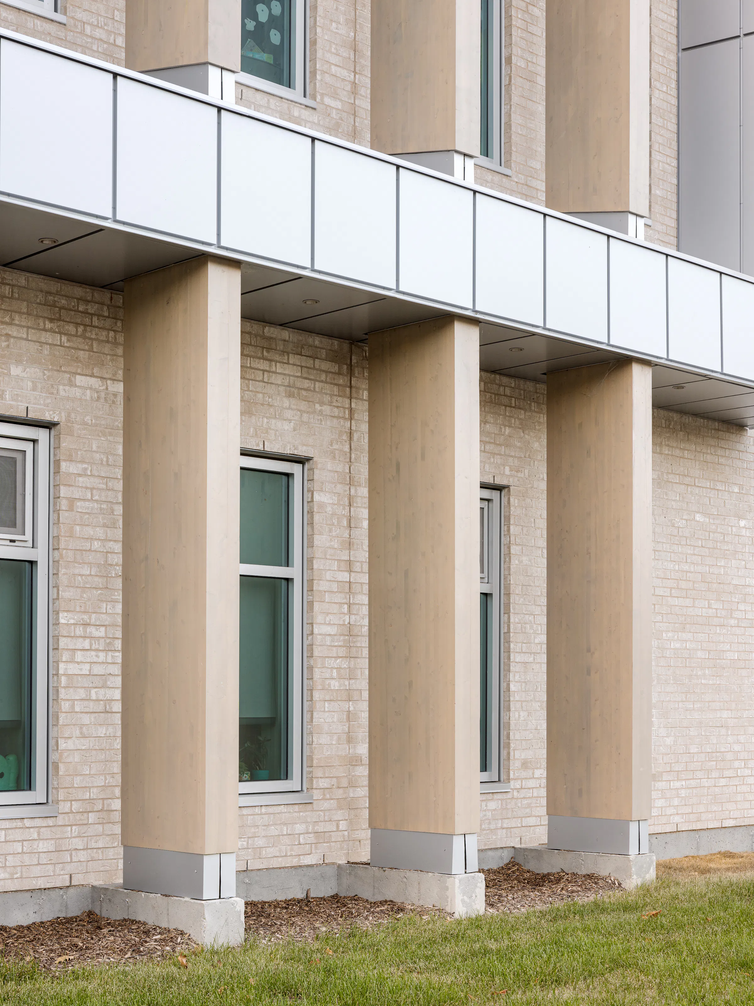 Architectural detail at the corner of the facade: repeating brick columns and continuous windows. Photo: TARMAC - Damien Ligiardi