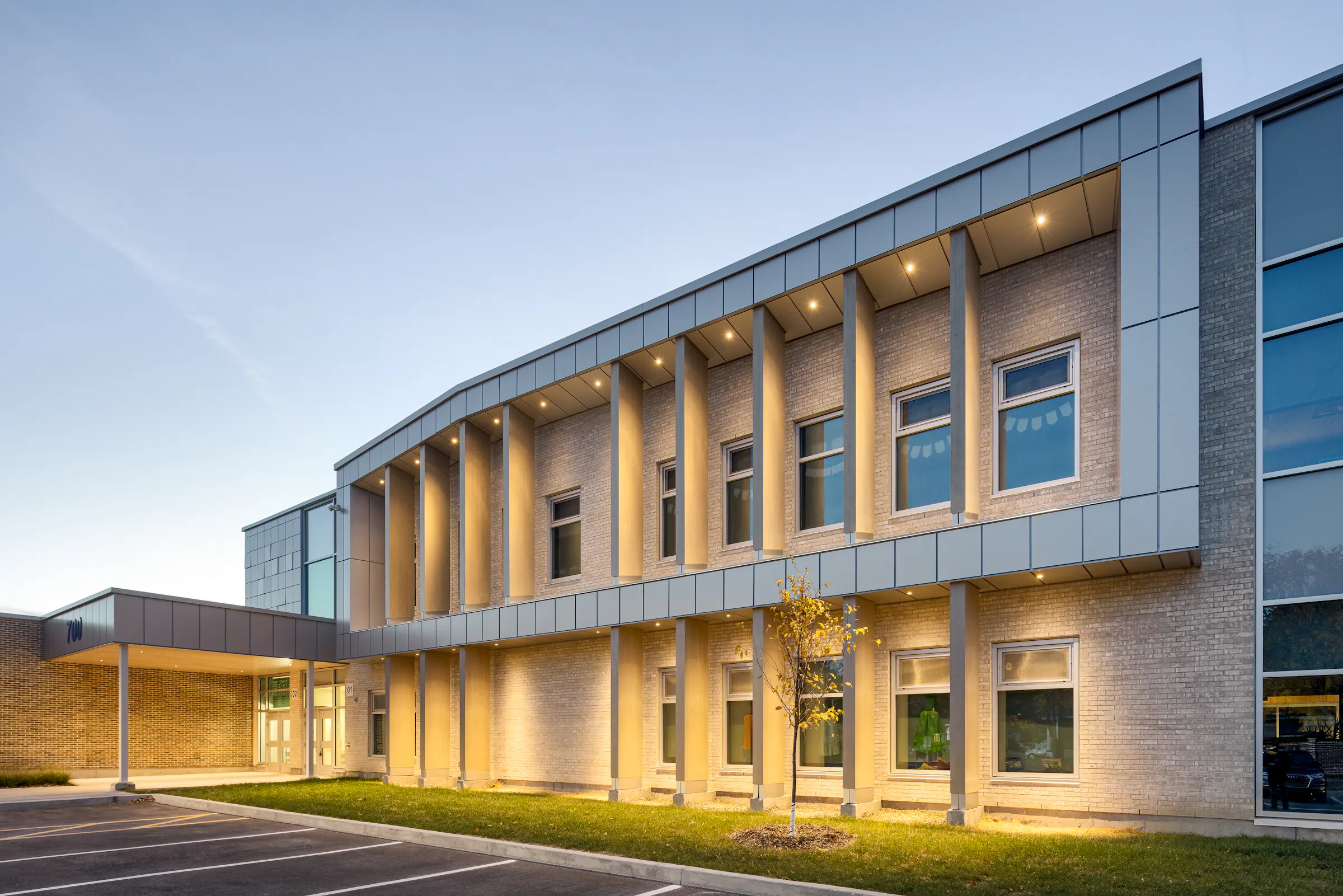 Angled view of the rear facade, two stories, mixed brick and aluminum cladding, late afternoon light. Photo: TARMAC - Damien Ligiardi
