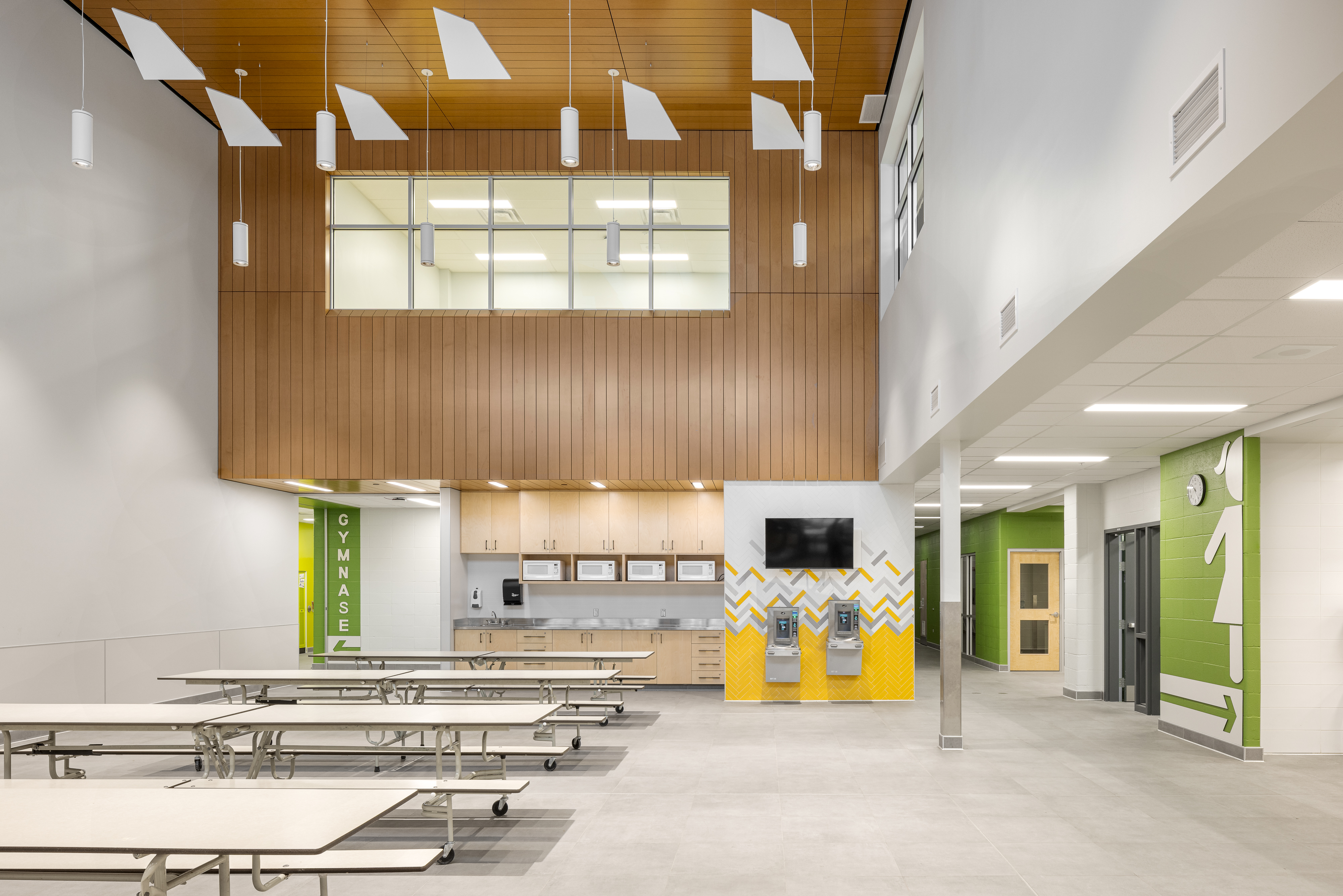 Dining hall at Bois-Joli–Sacré-Coeur school, cafeteria tables and wooden ceiling with yellow and green accents. Photo: TARMAC - Damien Ligiardi
