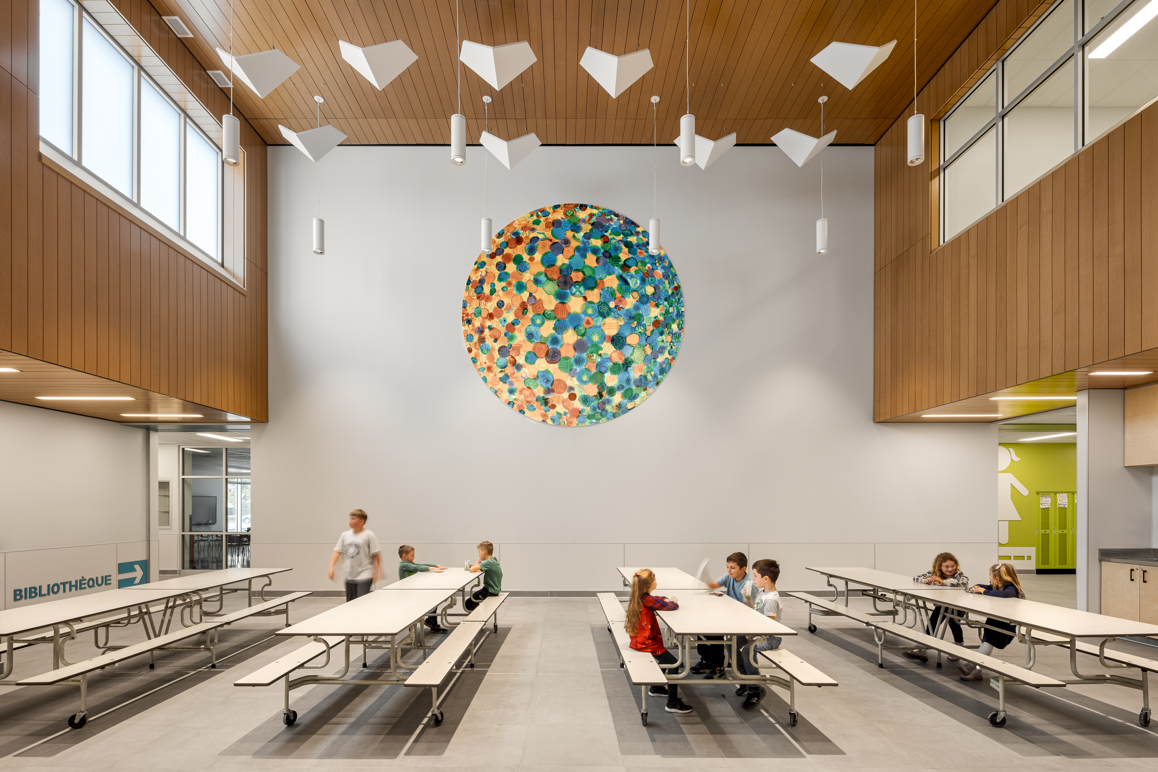 Overview of the cafeteria with colorful wall sculpture, wooden slat ceiling, and large windows. Photo: TARMAC - Damien Ligiardi