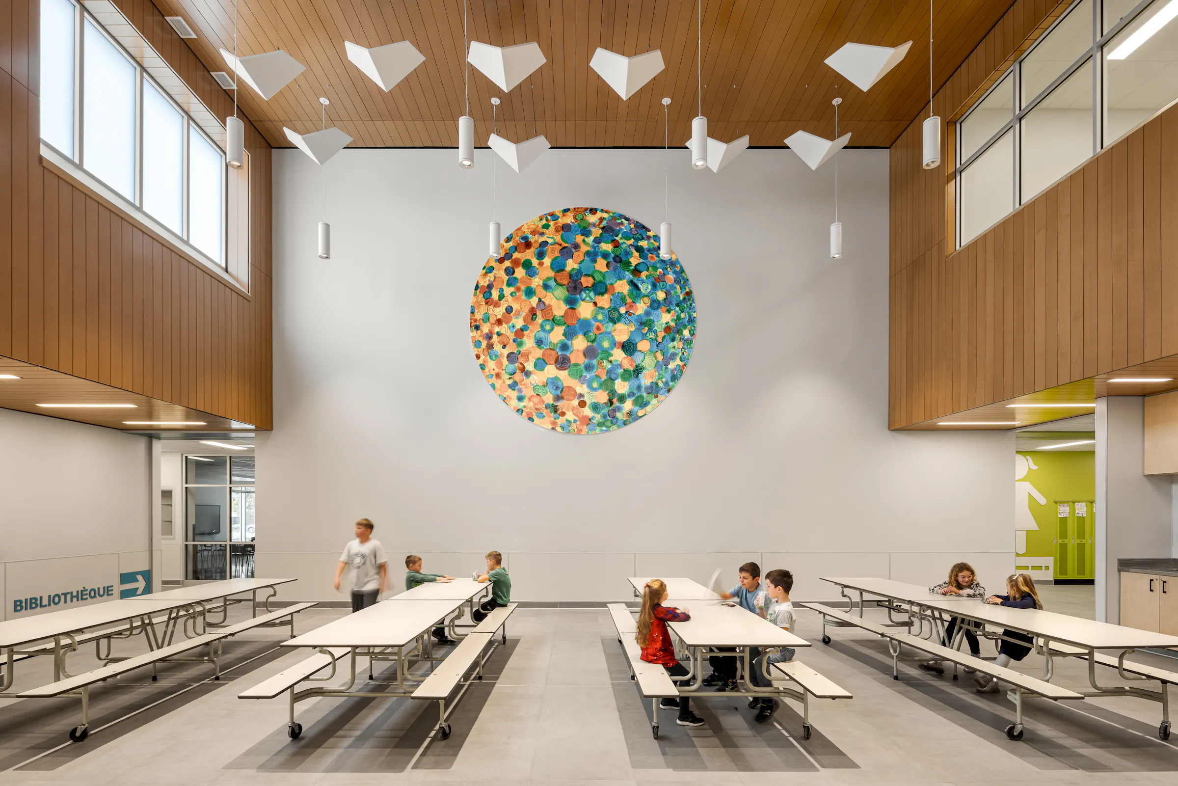 Overview of the cafeteria with colorful wall sculpture, wooden slat ceiling, and large windows. Photo: TARMAC - Damien Ligiardi