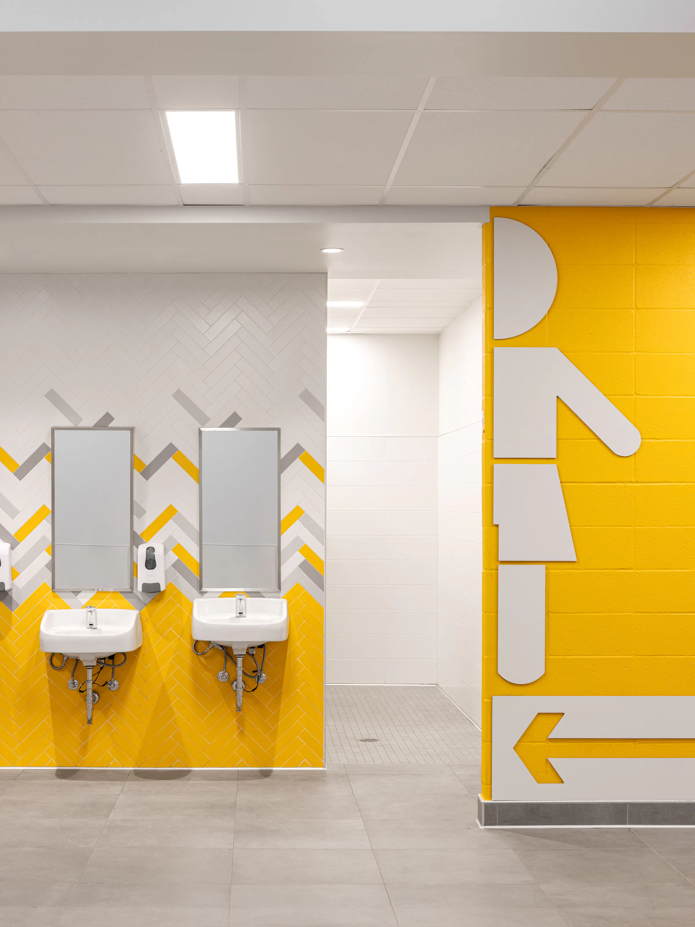 Cafeteria washroom area with yellow and green chevron-patterned wall and integrated soap dispenser. Photo: TARMAC - Damien Ligiardi