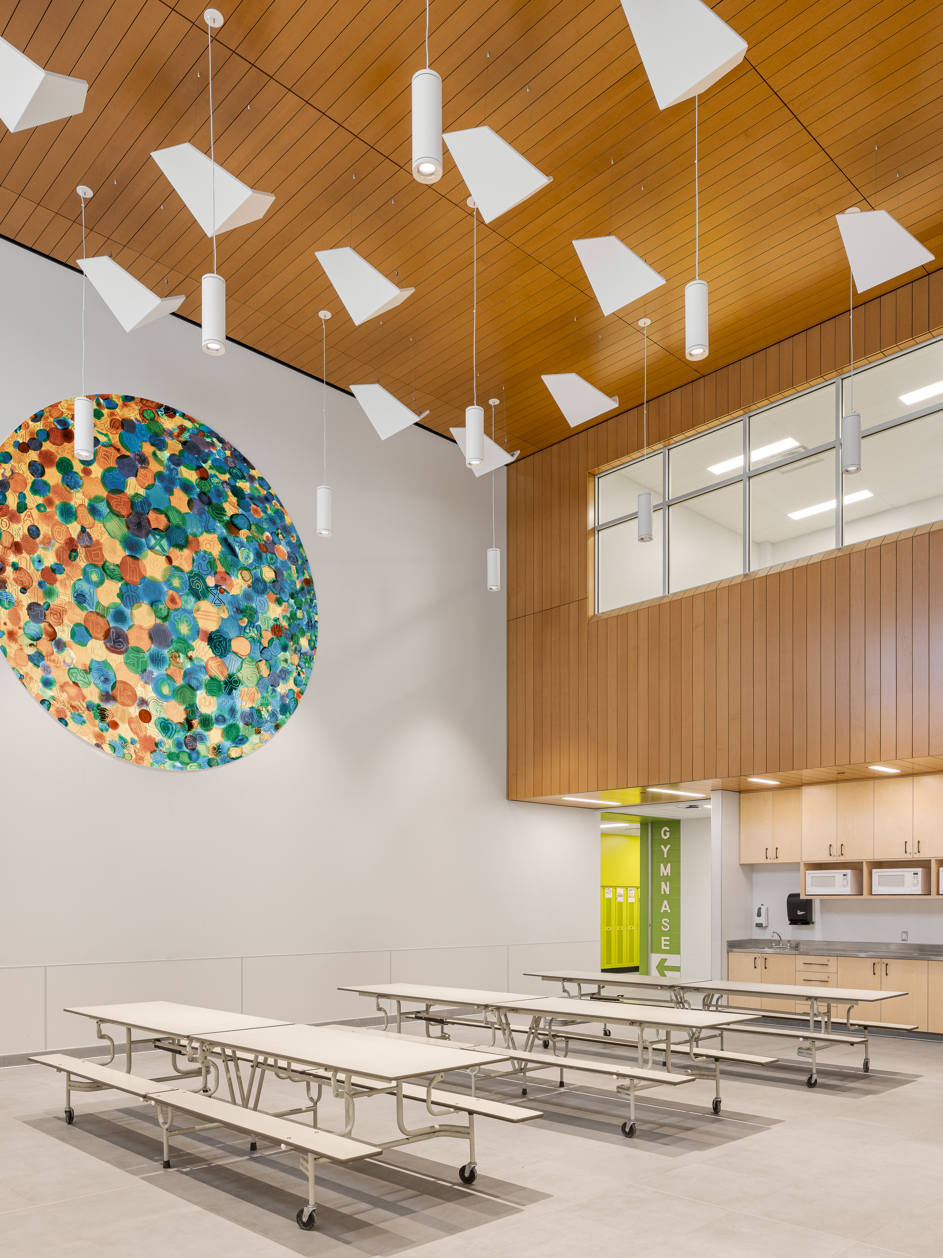 Overview of the cafeteria with colorful wall sculpture, wooden slat ceiling, and large windows. Photo: TARMAC - Damien Ligiardi