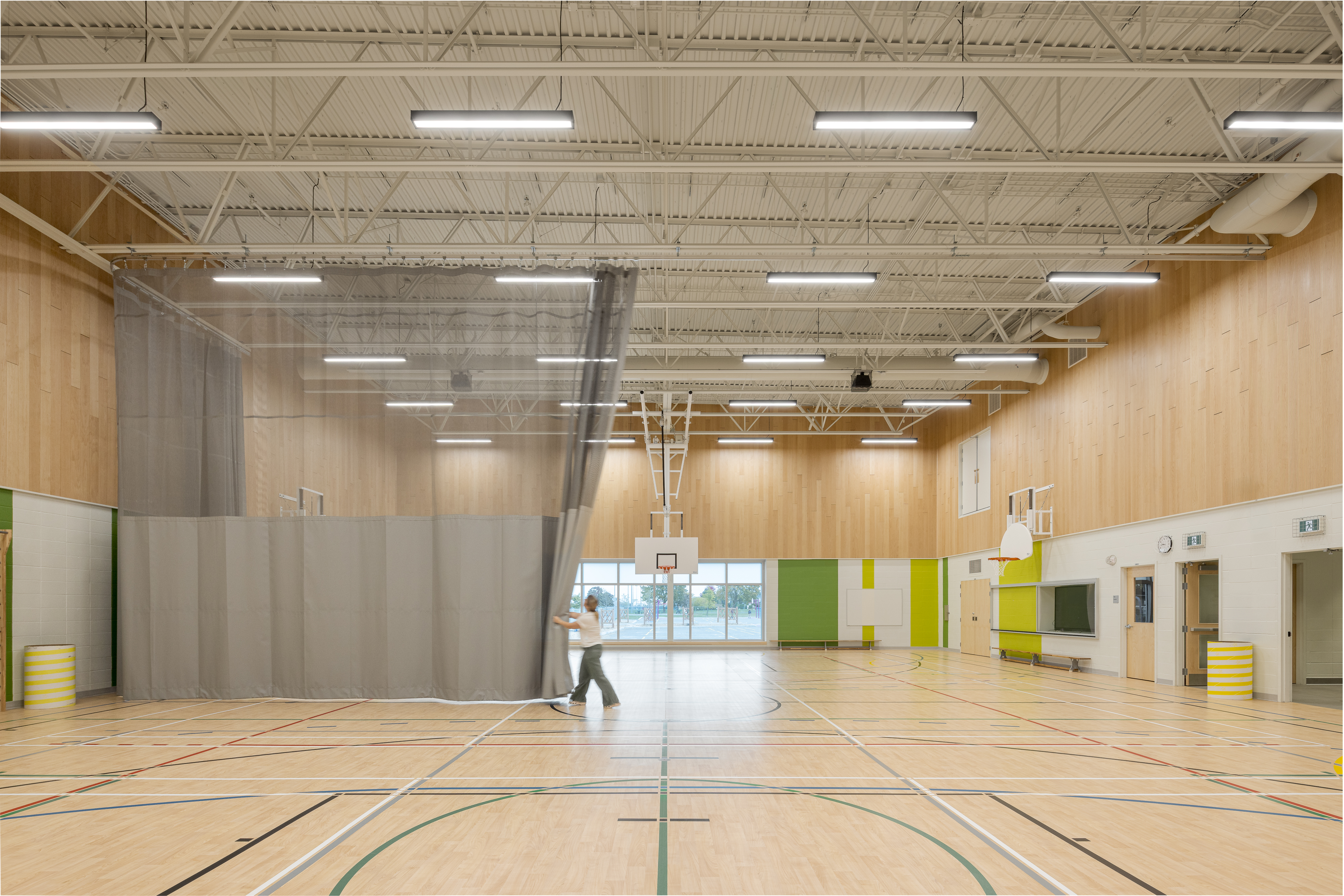 Overview of the double gymnasium, wooden walls and sports equipment, high ceilings. Photo: TARMAC - Damien Ligiardi