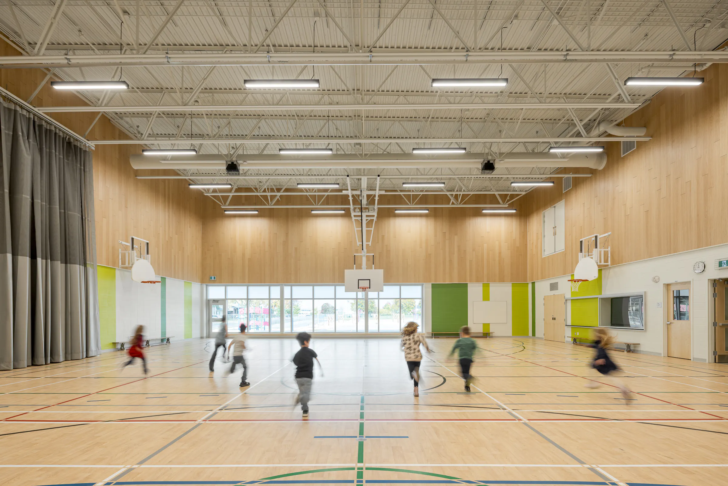 The double gymnasium at Bois-Joli–Sacré-Coeur school, a laminated wood structure, with students practicing on the sports floor. Photo: TARMAC - Damien Ligiardi
