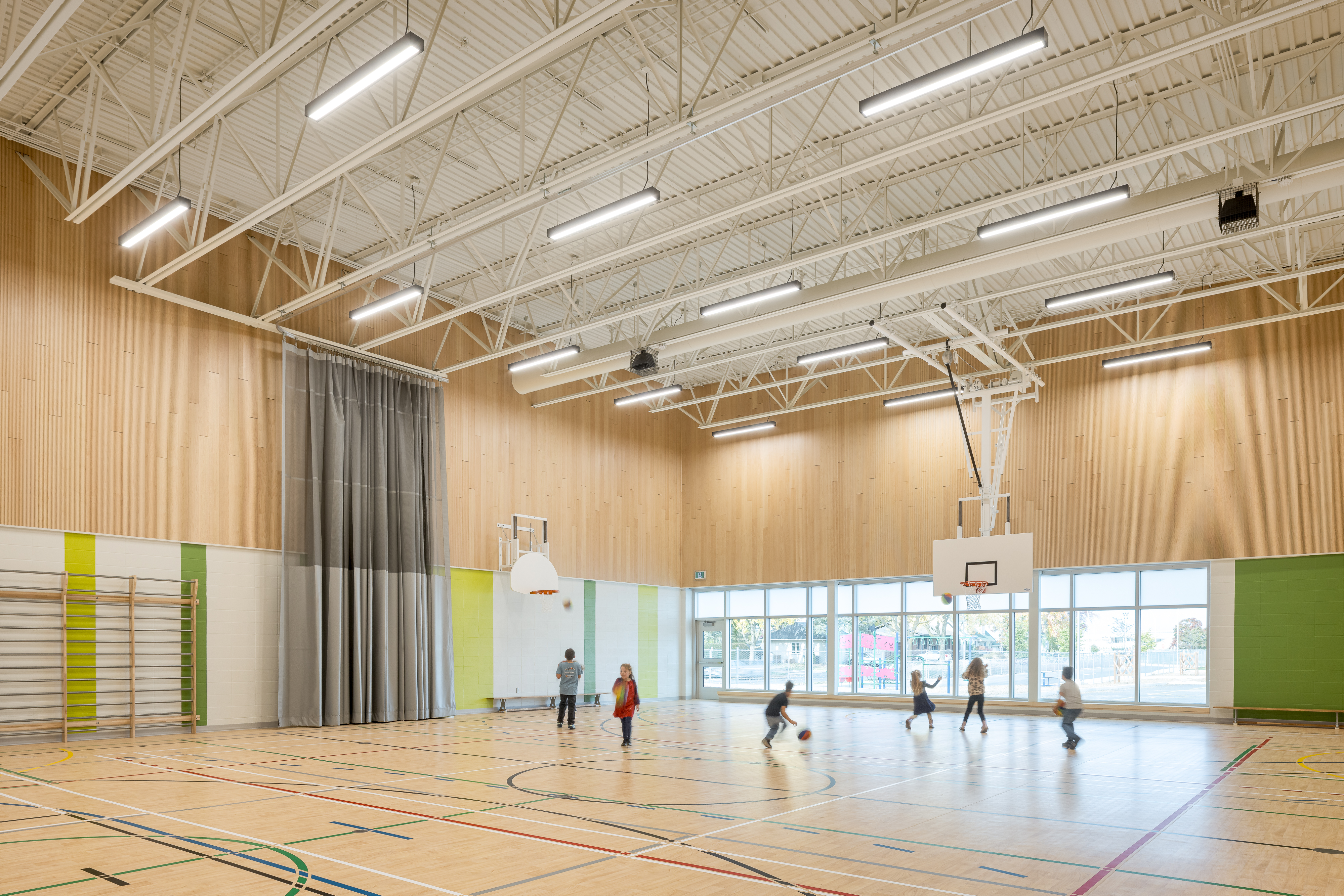 Overview of the double gymnasium, wooden walls and sports equipment, high ceilings. Photo: TARMAC - Damien Ligiardi
