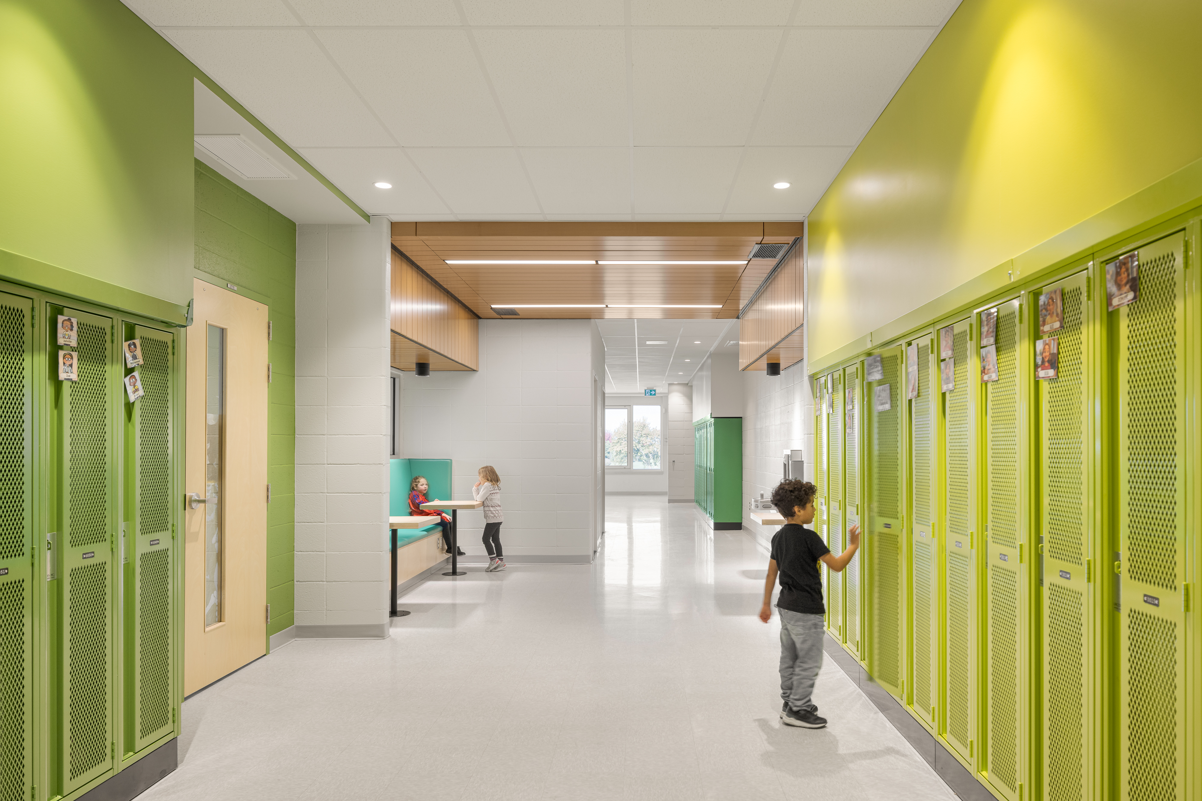School corridor with green and yellow lockers, built-in study alcoves, and students moving around. Photo: TARMAC - Damien Ligiardi