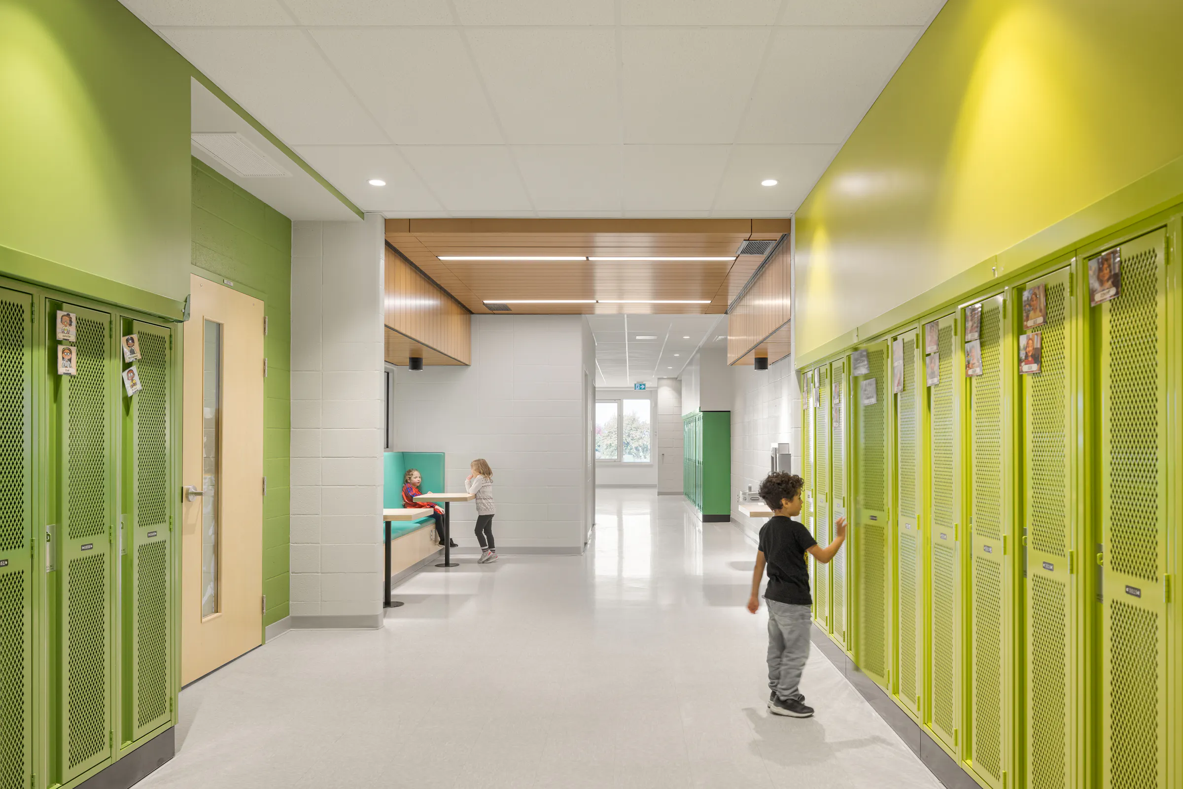 School corridor with green and yellow lockers, built-in study alcoves, and students moving around. Photo: TARMAC - Damien Ligiardi