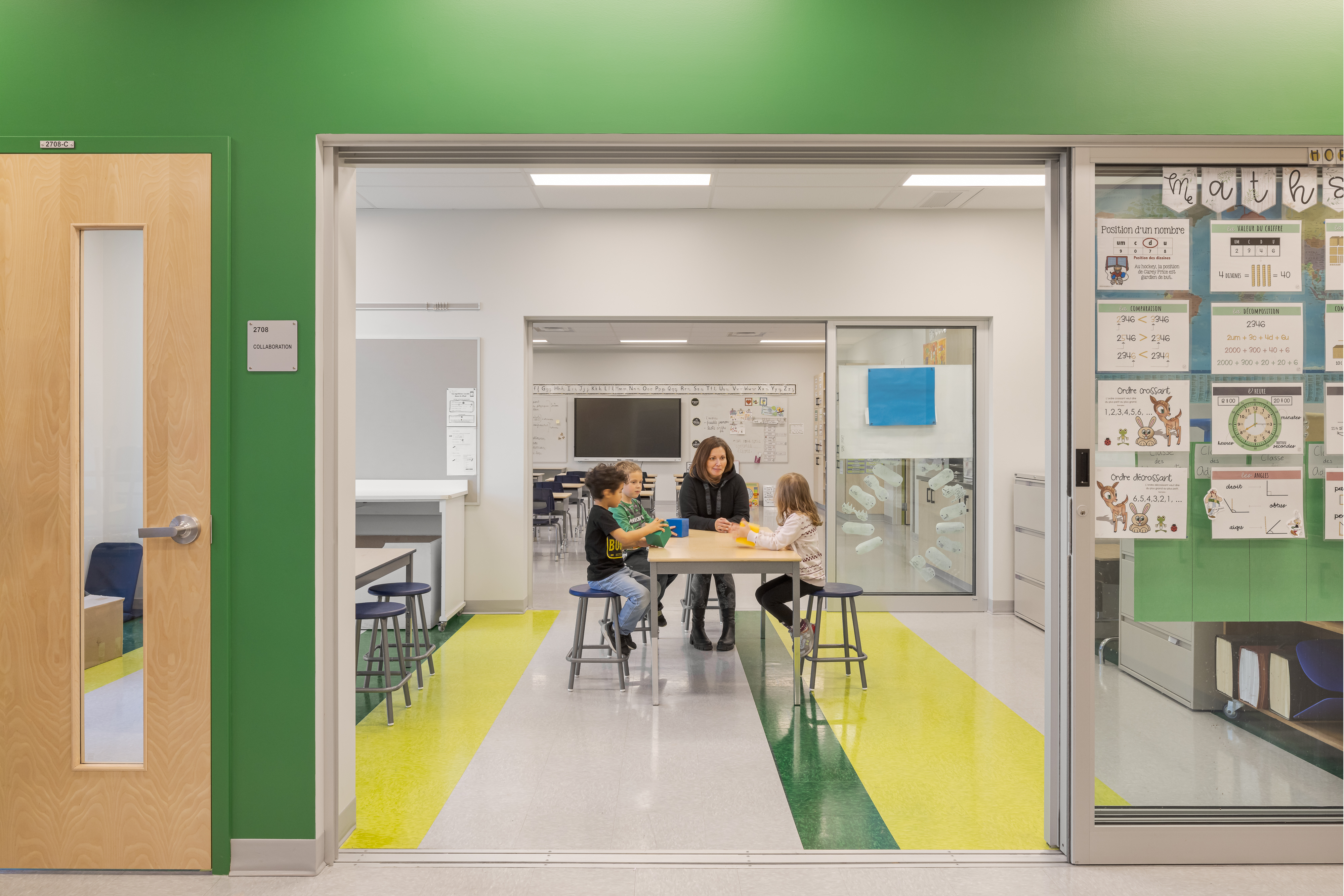 A glass-walled collaborative workspace adjacent to the classrooms, with students engaged in activities, modular furniture, and a whiteboard. Photo: TARMAC - Damien Ligiardi