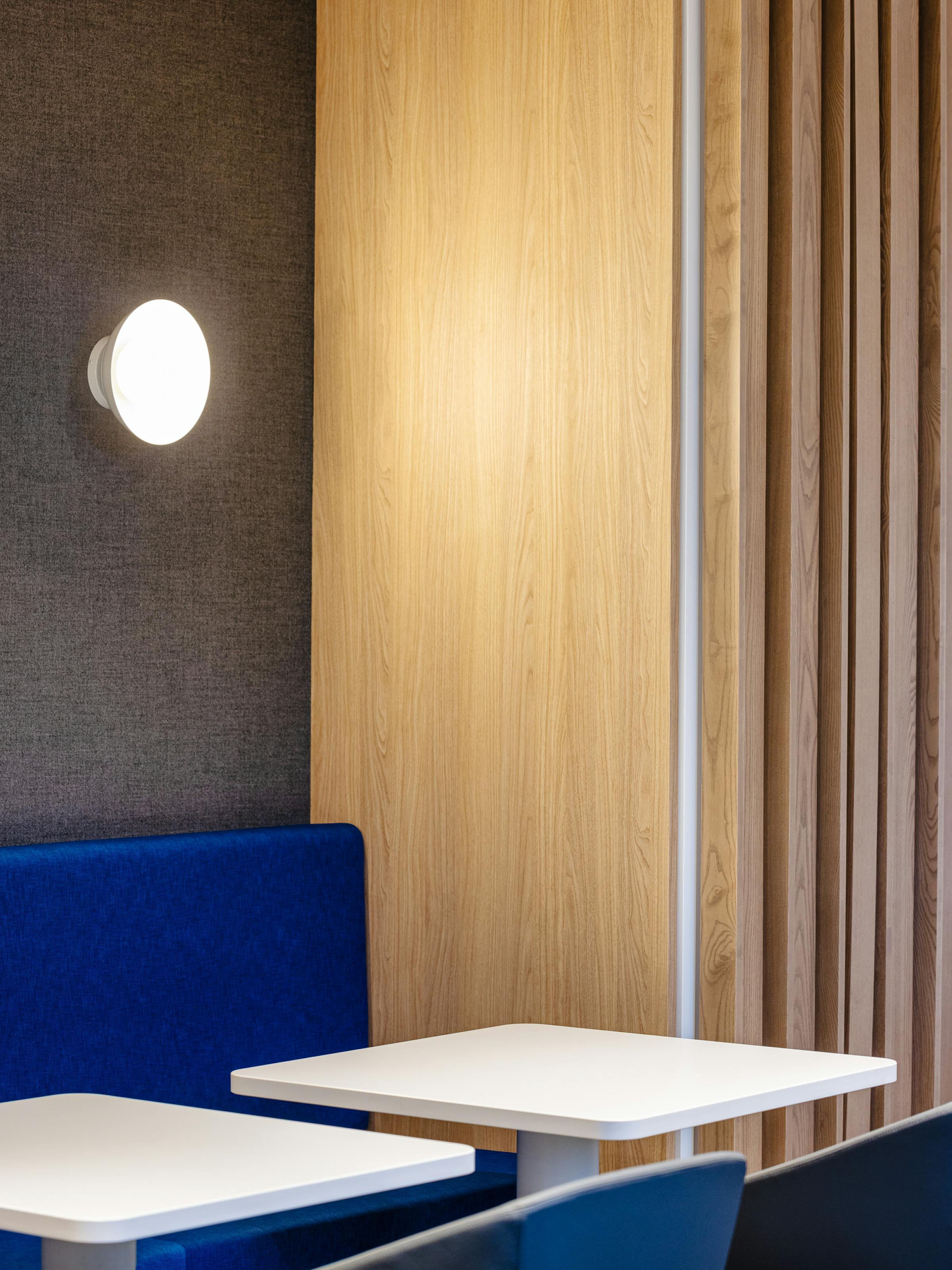 Detail of the lighting design with white tables and blue benches.