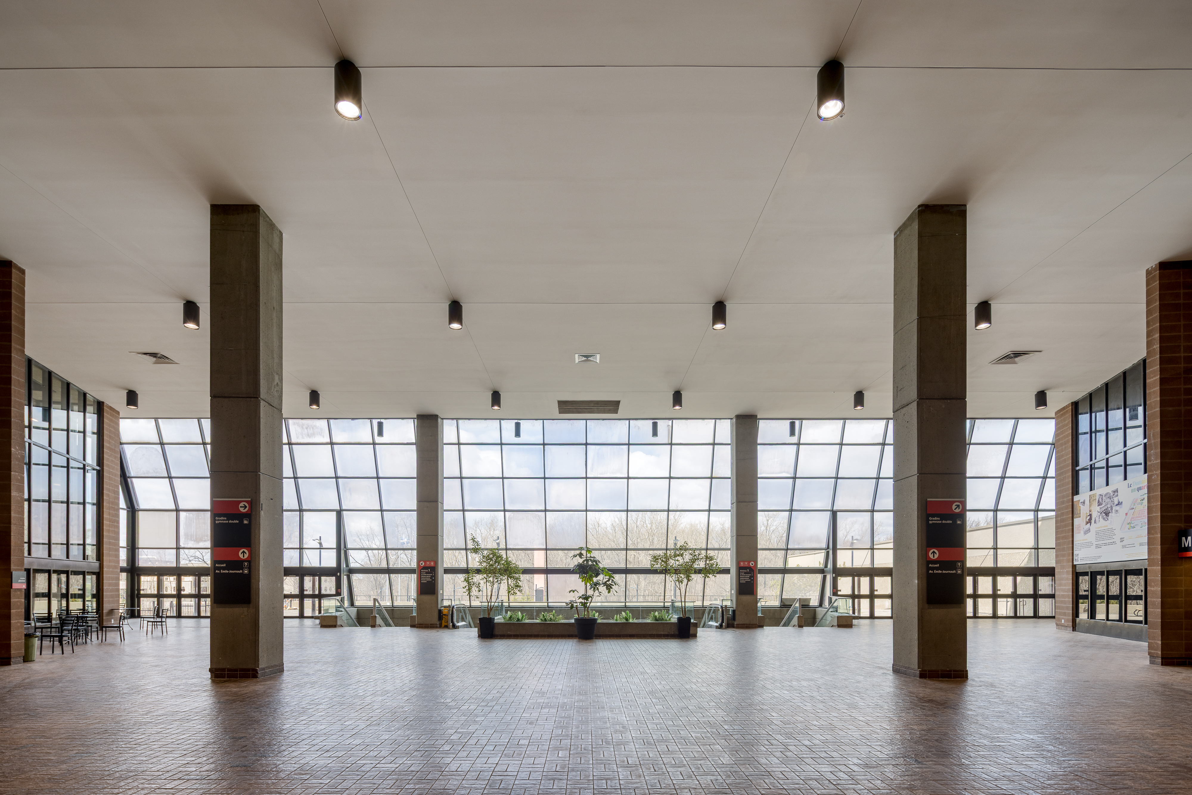 Architectural photograph of the entrance hall with concrete columns and natural lighting, Claude-Robillard Sports Complex.