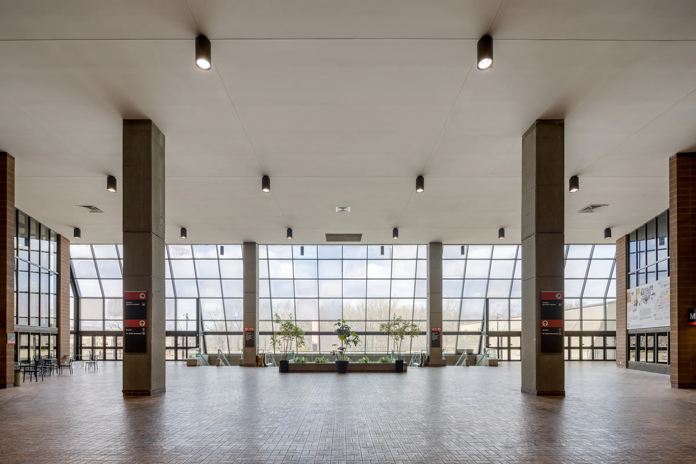 Architectural photograph of the entrance hall with concrete columns and natural lighting, Claude-Robillard Sports Complex.