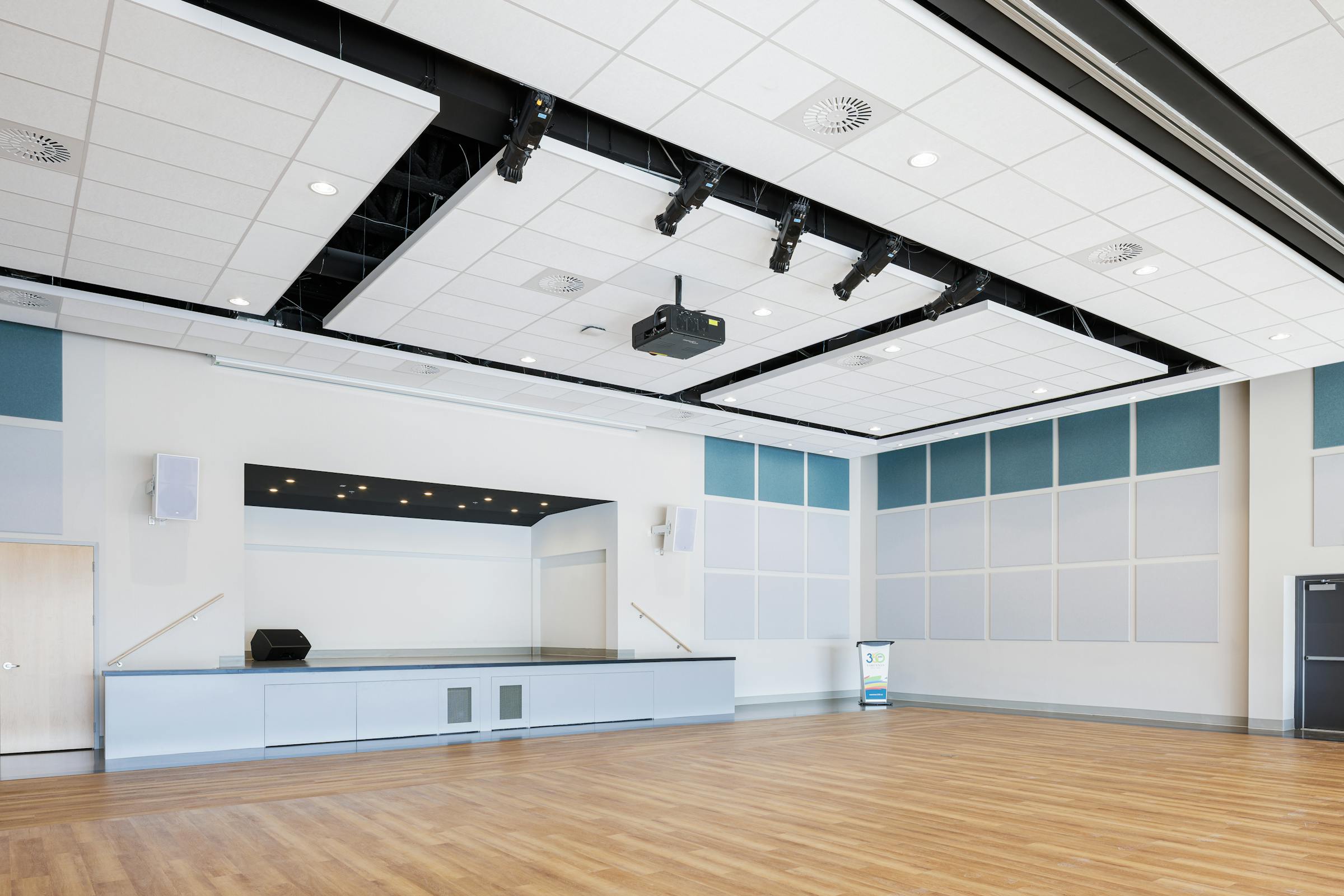 Photographie d'architecture d'intérieur d'une salle multi fonctionnelle au couleur neutre avec des accents bleu.