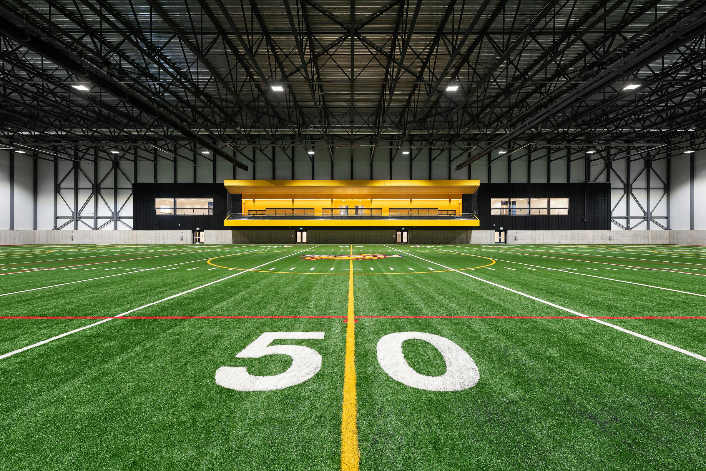 Vue à un point de fuite de l'estrade jaune dans un centre sportif intérieur. La surface de jeux est au premier plan.
